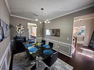 Dining area featuring chair rail molding, dark wood-finish flooring, and a modern chandelier