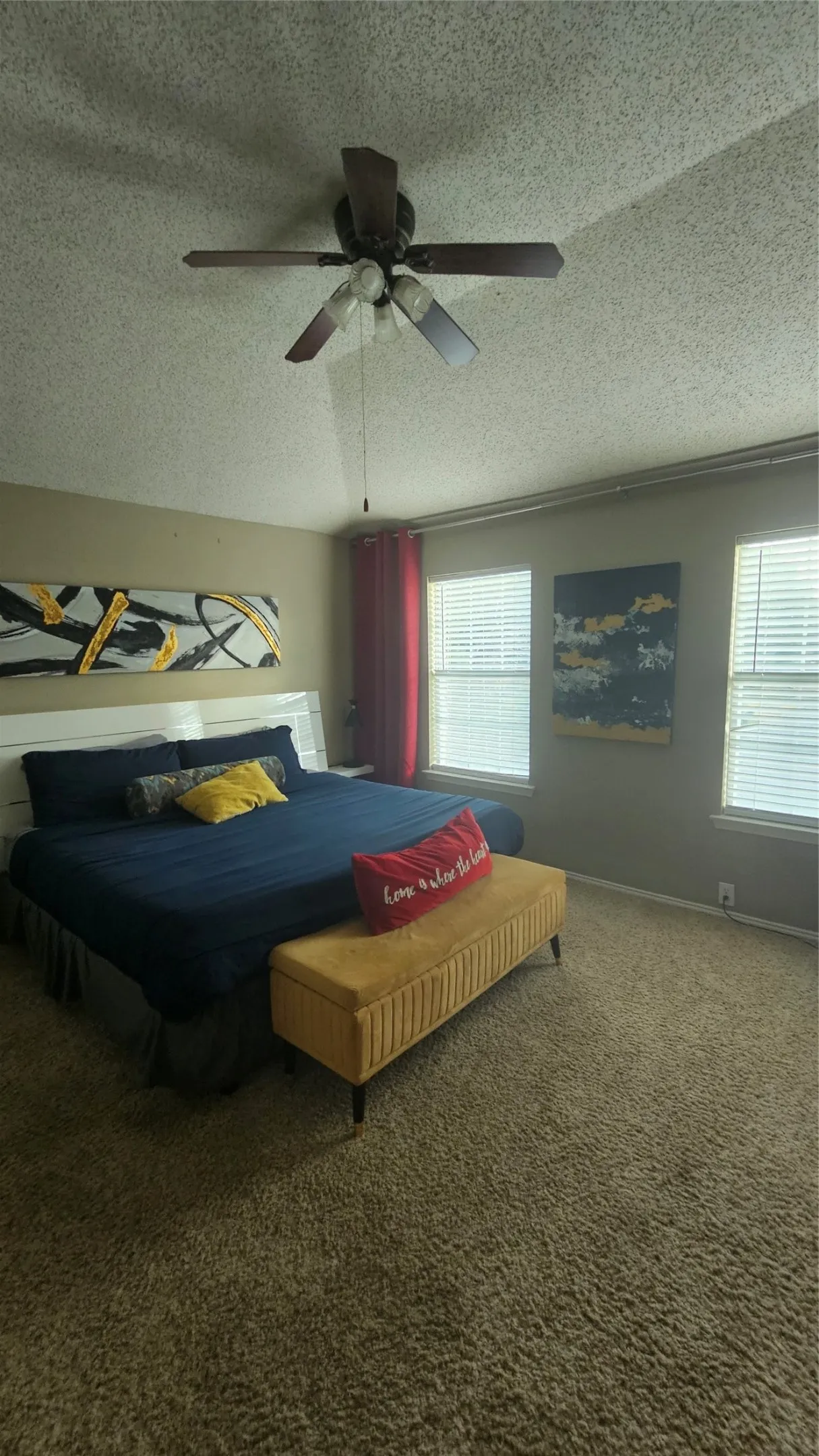 Textured carpeting, multiple windows with blinds, and a ceiling fan with integrated lighting
