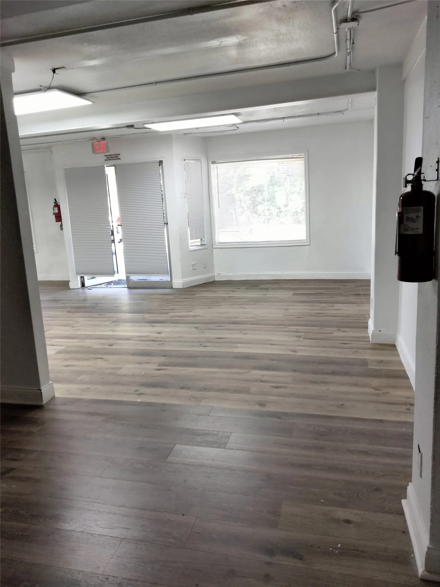 Spacious interior with wood-finish flooring, white walls, and track lighting