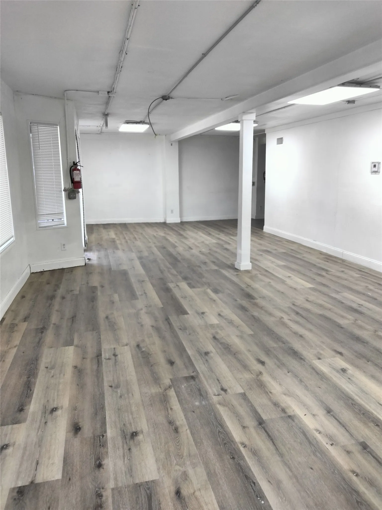 Expansive room featuring light wood-finish flooring and white walls