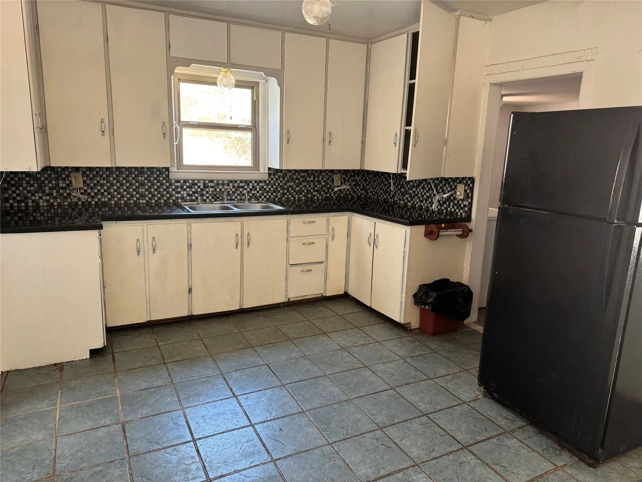 Tiled open kitchen and dining area. Utility room behind fridge. Fridge, washer, and dryer stay.