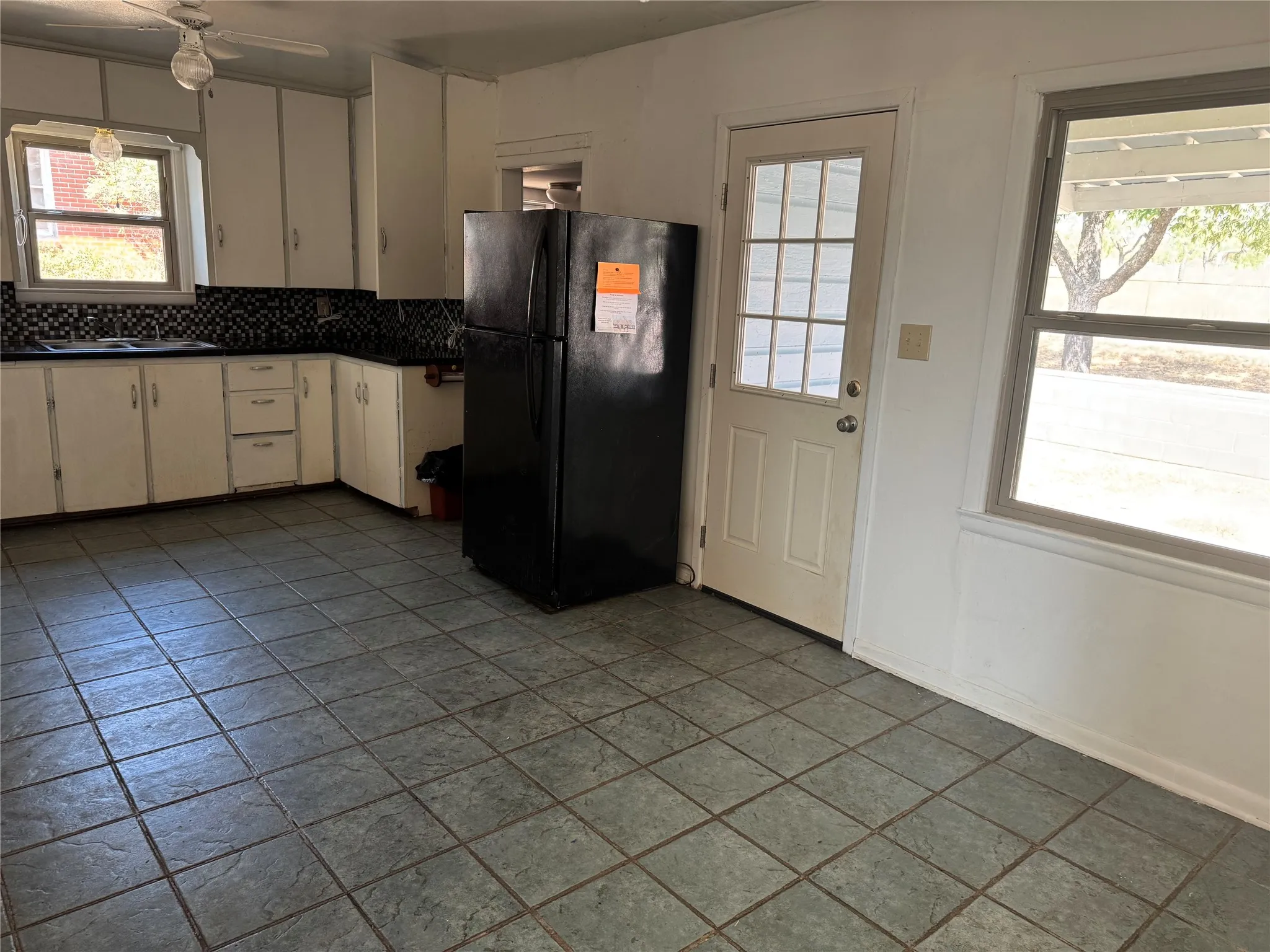 Tiled open kitchen and dining area. Back door. Utility room behind fridge. Fridge, washer, and dryer stay.