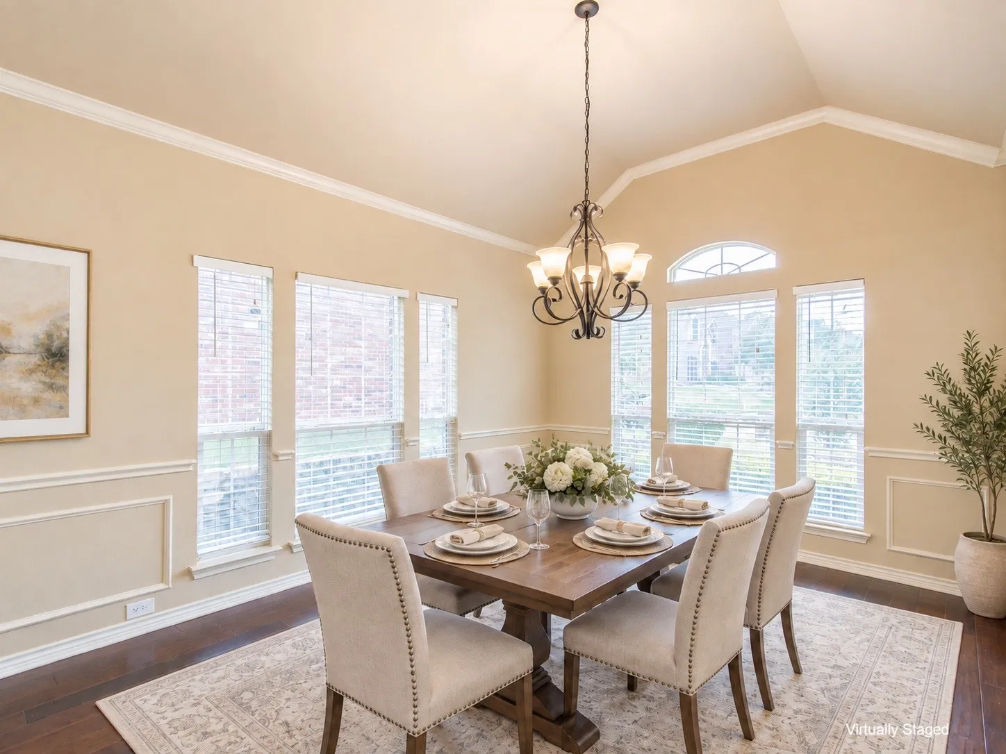 Vaulted ceiling featuring crown molding, dark wood-finish flooring, multiple windows, and a classic chandelier