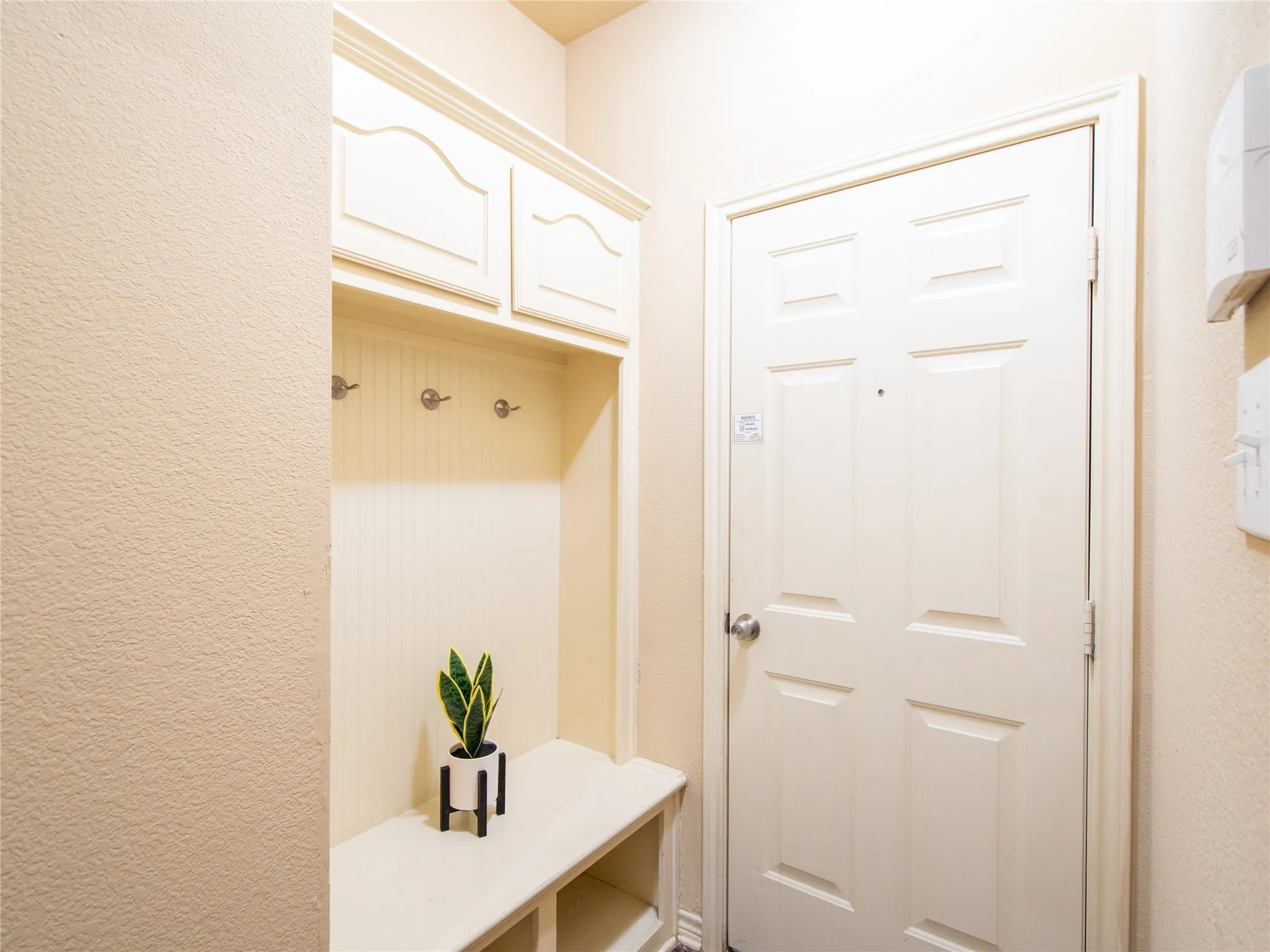 Built-in hall tree with upper cabinetry, beadboard backing, and integrated coat hooks