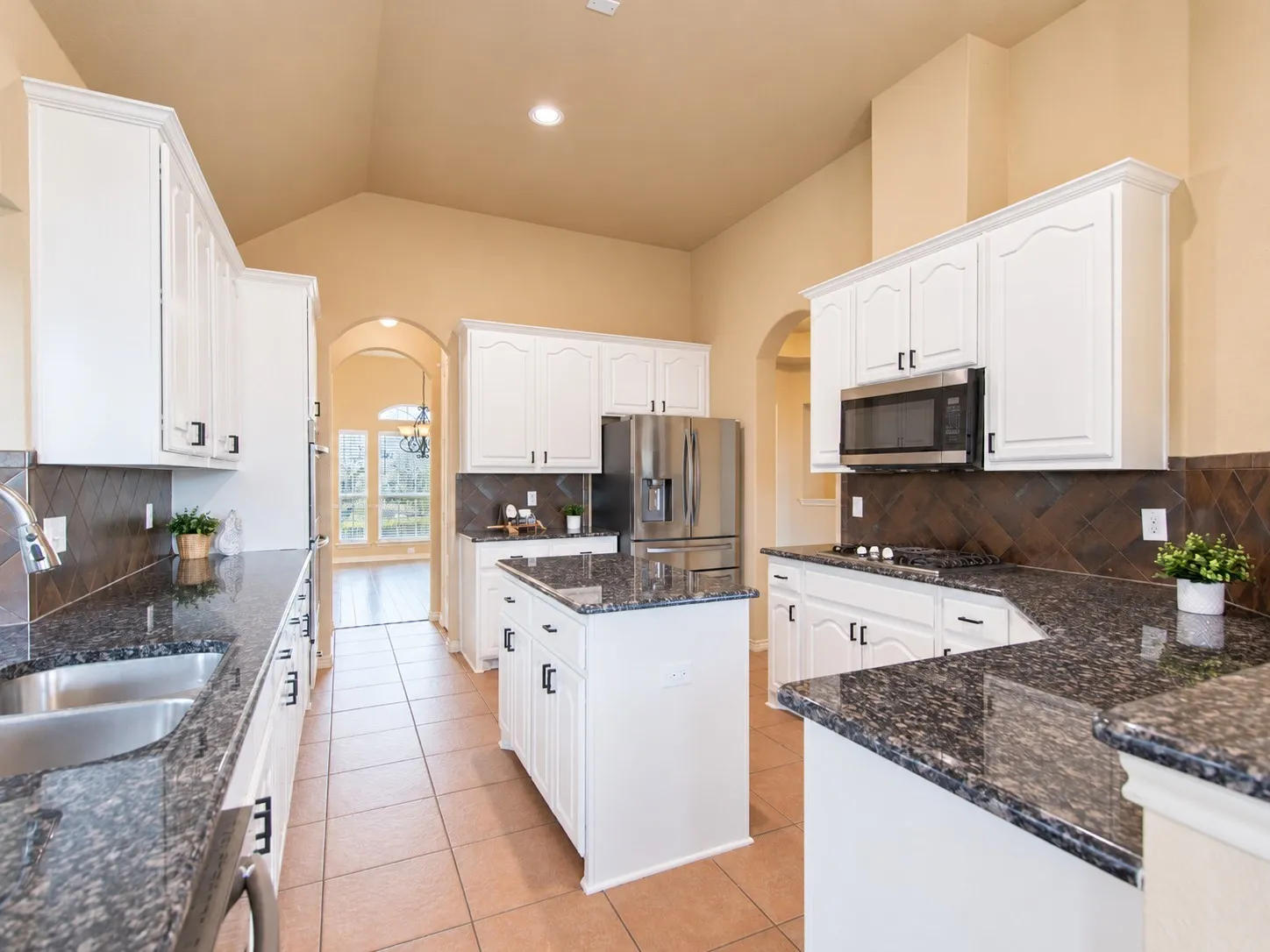 Kitchen featuring white cabinetry, dark stone countertops, stainless steel appliances, and a central island