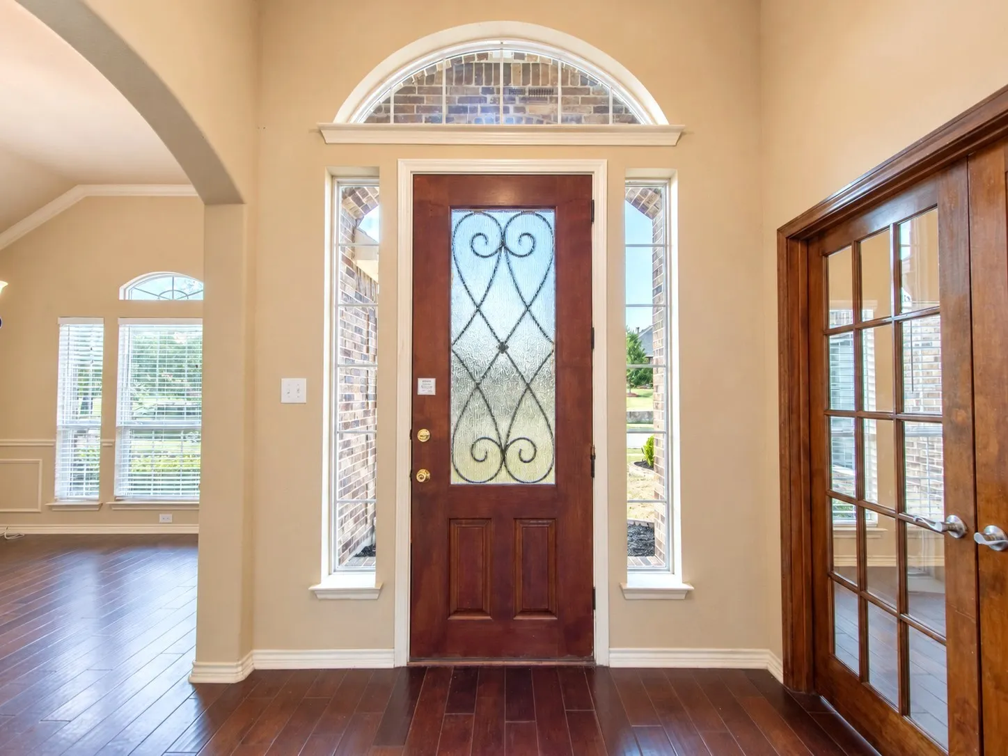 Arched entryway with a decorative glass-paneled door and sidelights