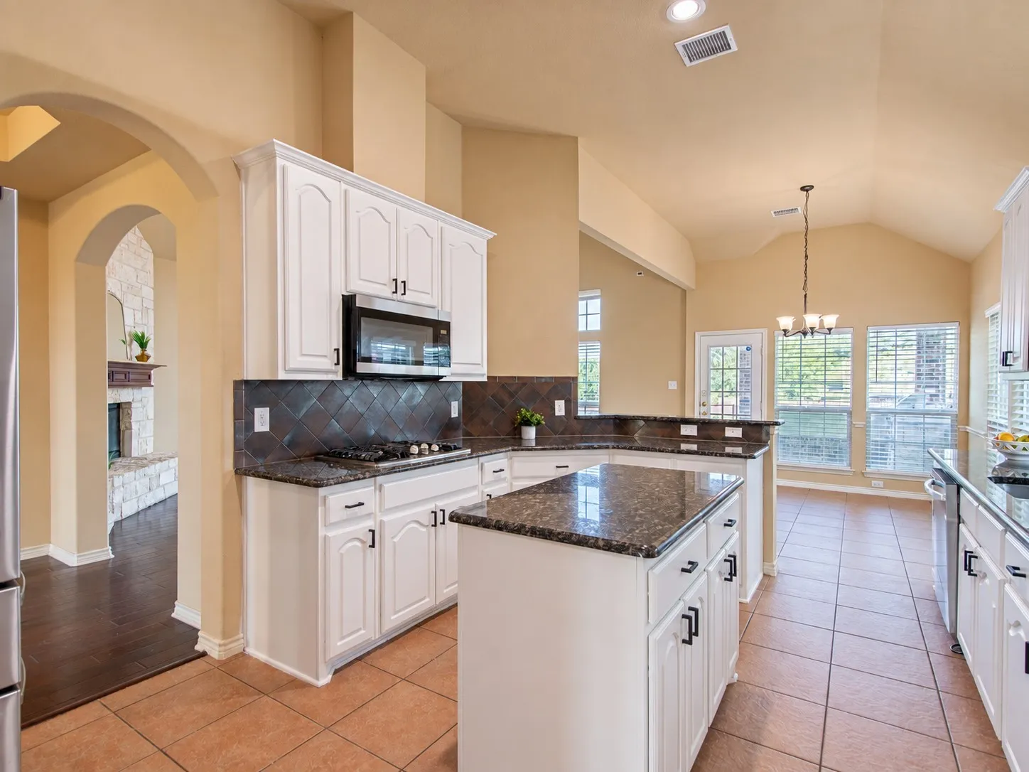 Kitchen featuring white cabinetry, dark stone countertops, a tile backsplash, and a central island