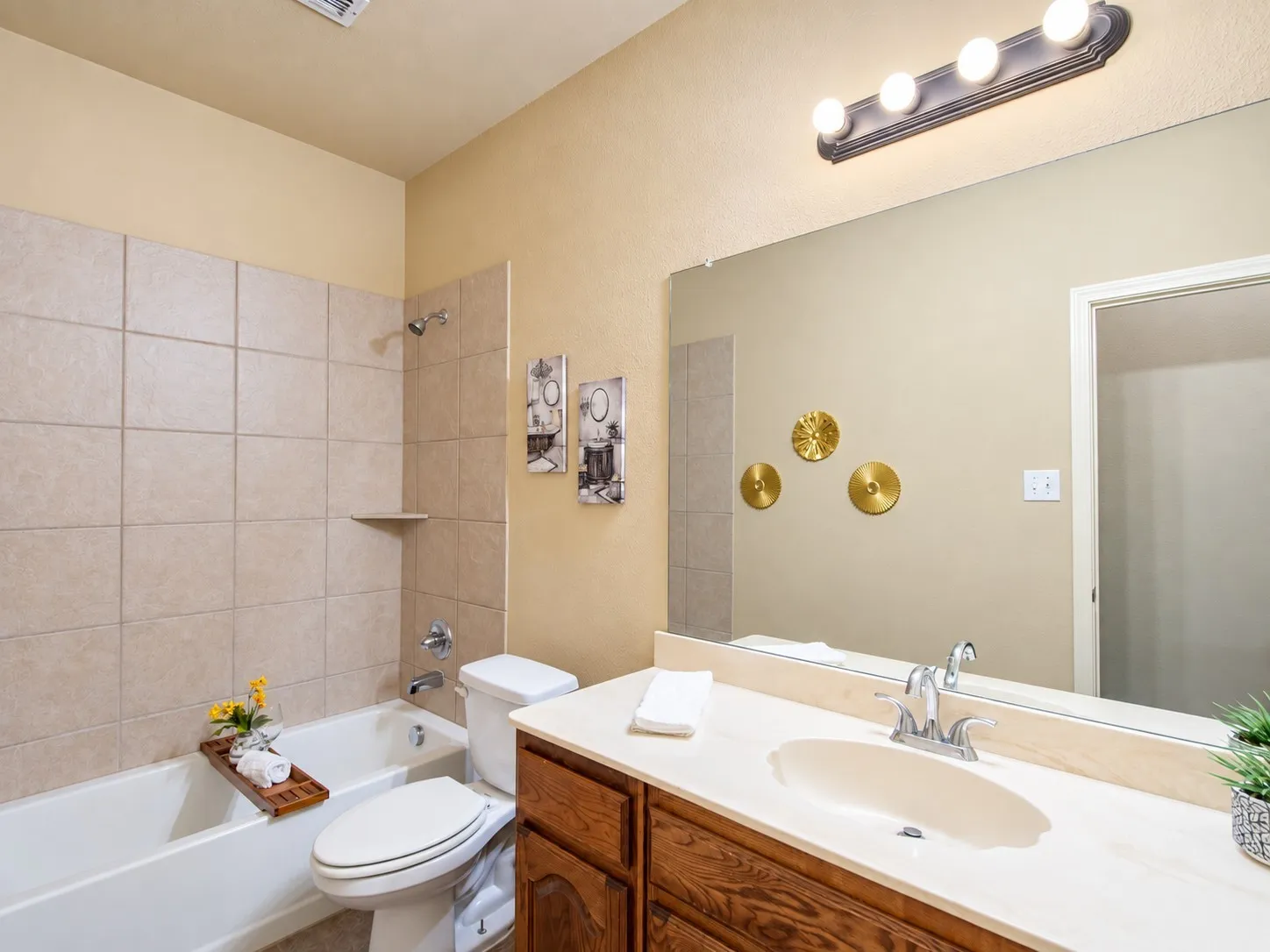 Bathroom featuring a tiled tub/shower combination, a vanity with a light-toned countertop, an integrated sink, and a built-in mirror
