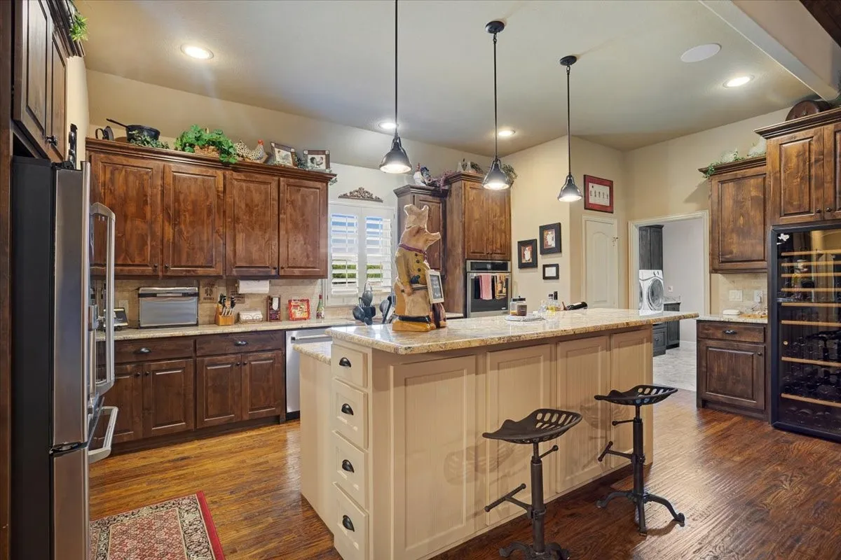 Wood-finish flooring, recessed lighting, and a kitchen island with pendant lighting