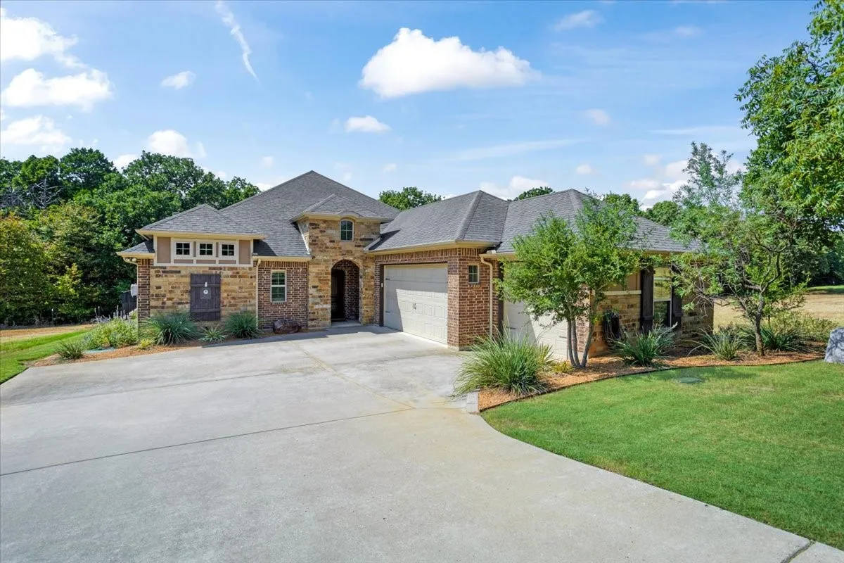 Brick and stone exterior with a dark shingle roof
