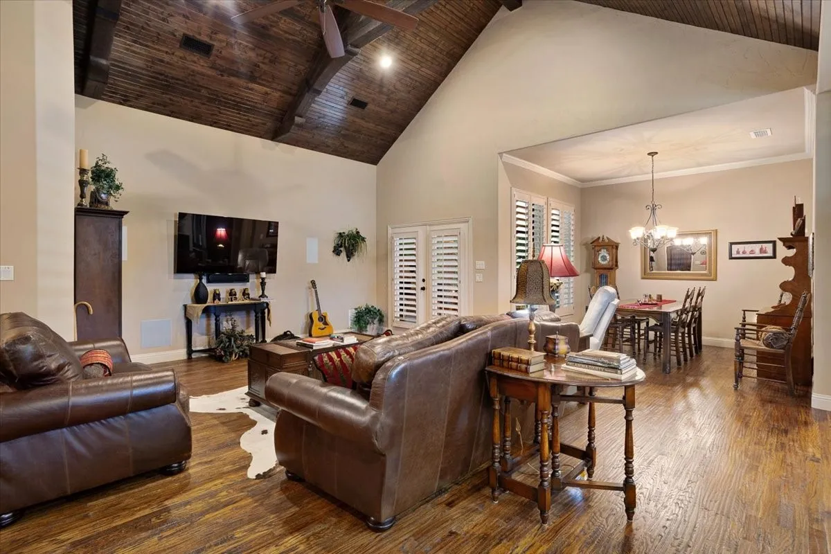 Vaulted wood-paneled ceiling, wood-finish flooring, plantation shutters, and a dining area with a chandelier