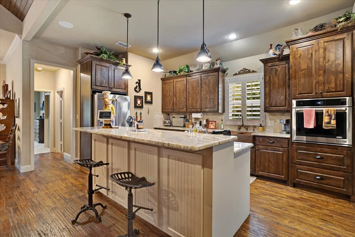 Kitchen featuring rich wood cabinetry, stainless steel appliances, a large island with a light-toned countertop, and recessed lighting