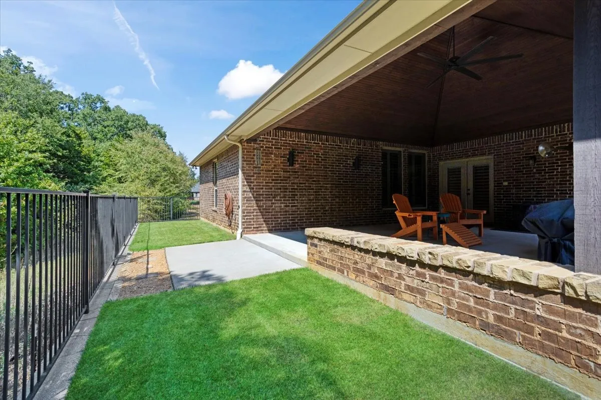 Covered patio with a high vaulted ceiling and ceiling fan, featuring a concrete surface