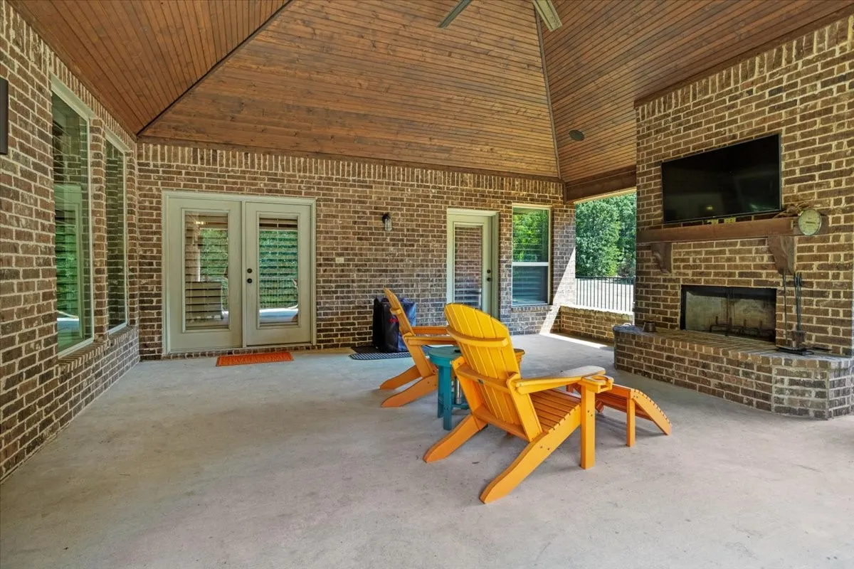 22x24 Covered patio featuring a brick exterior, wood plank ceiling, an outdoor fireplace, and multiple​​‌​​​​‌​​‌‌​‌‌​​​‌‌​‌​‌​‌​​​‌​​ windows