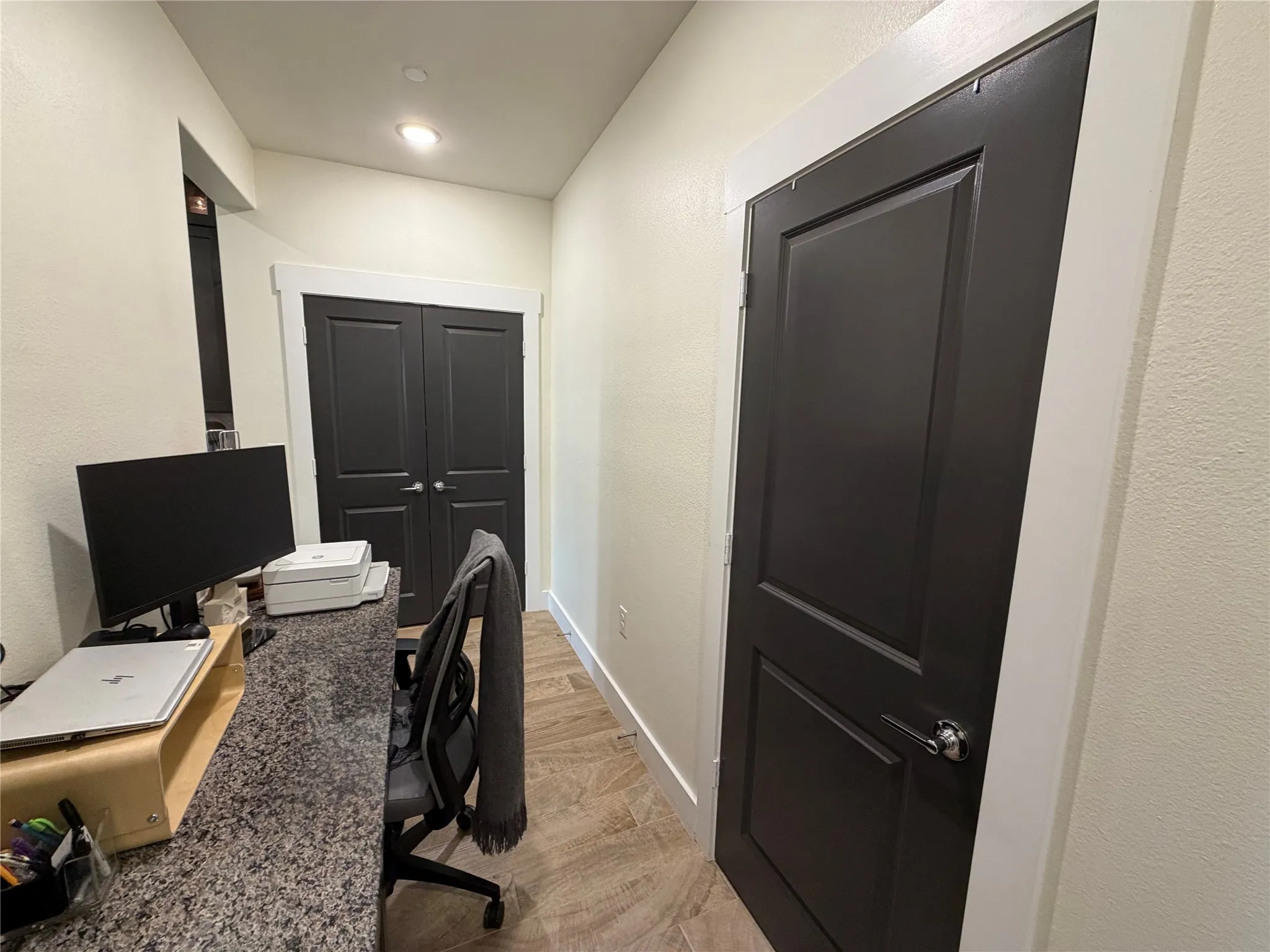 The office space has a desk with a granite countertop and entry to the pantry and coat closet