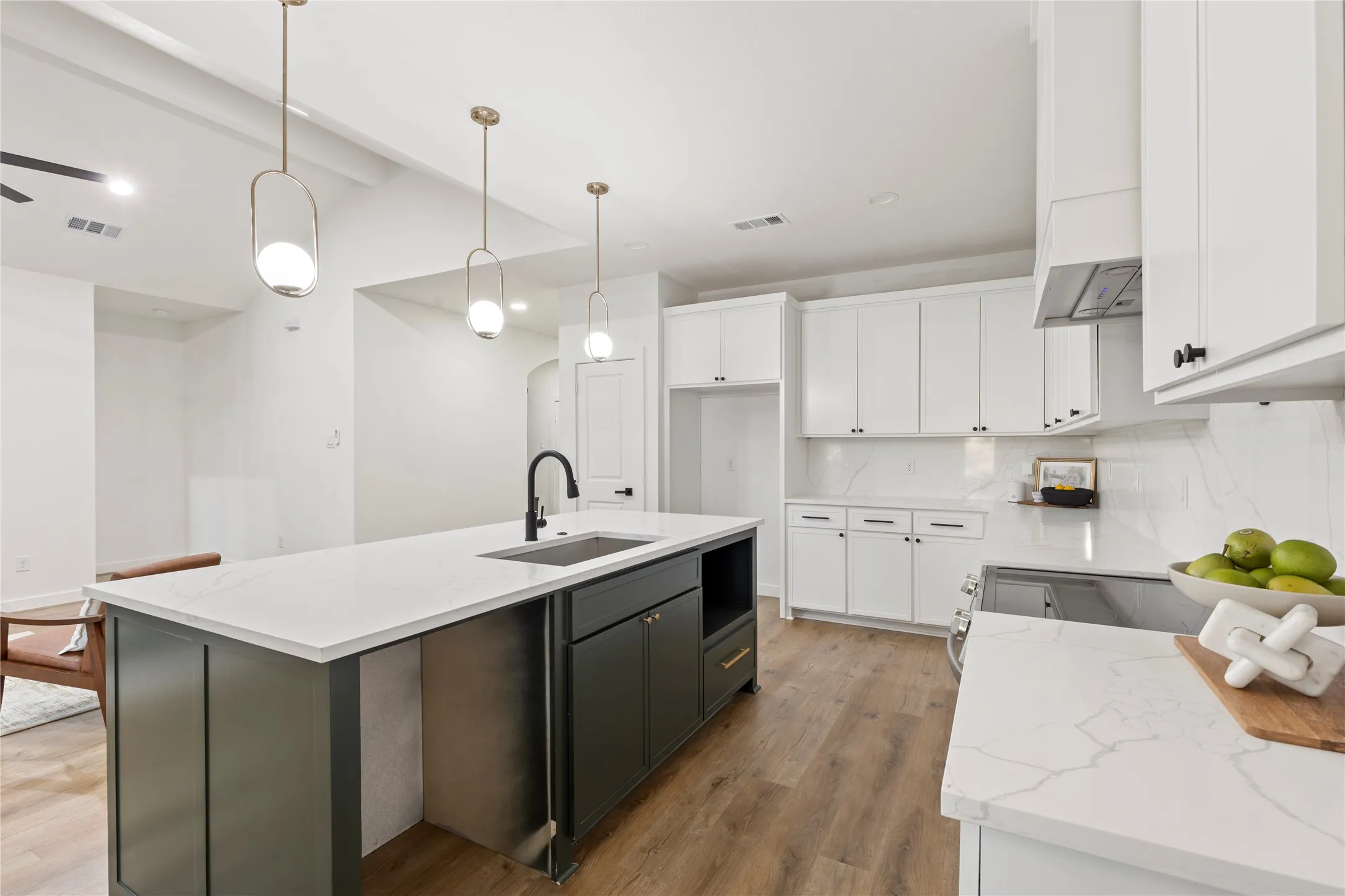 Kitchen featuring a waterfall-edge island with integrated sink, white cabinetry, integrated range hood, and wood-finish flooring