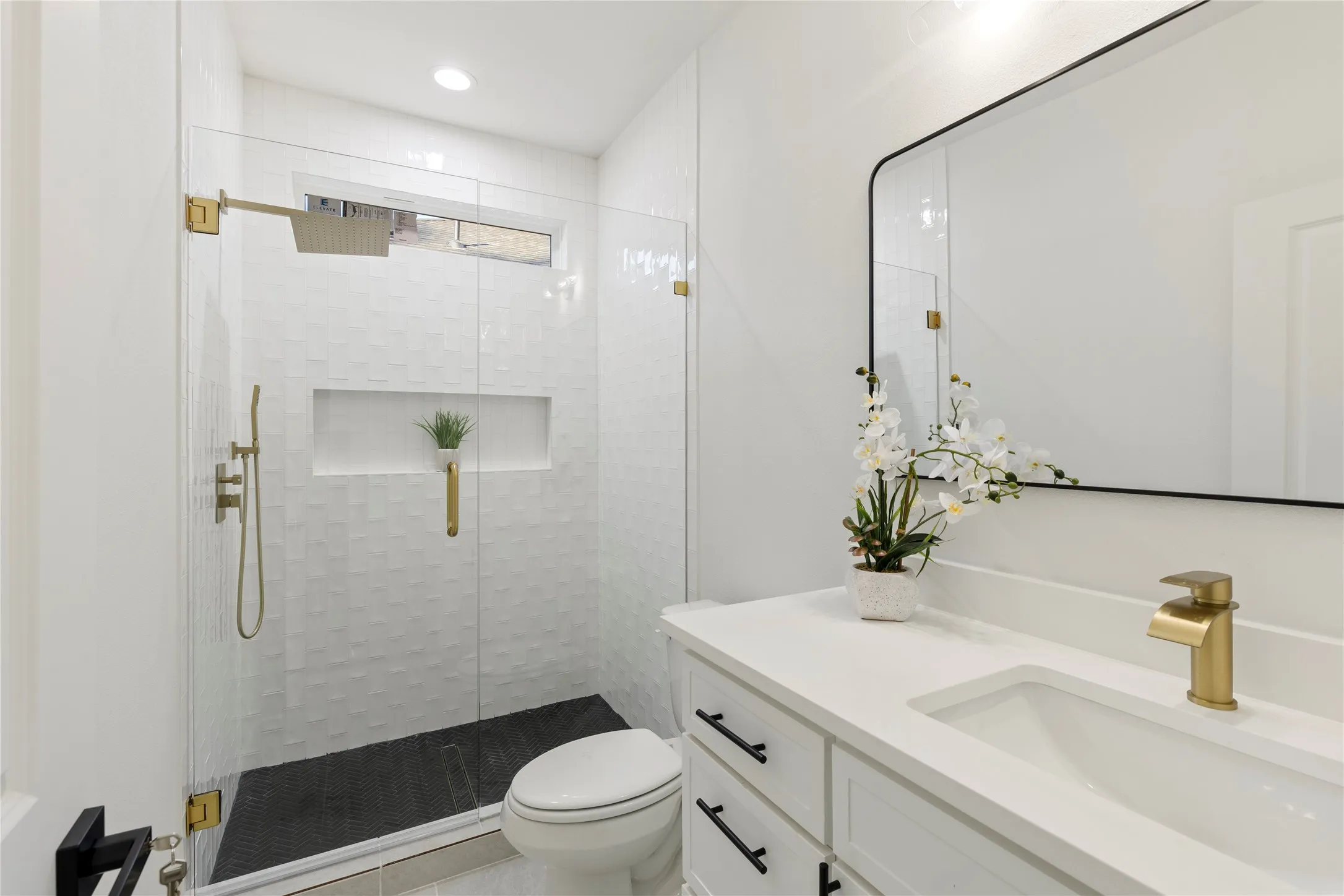 Glass-enclosed shower with gold-tone fixtures and a recessed shelf