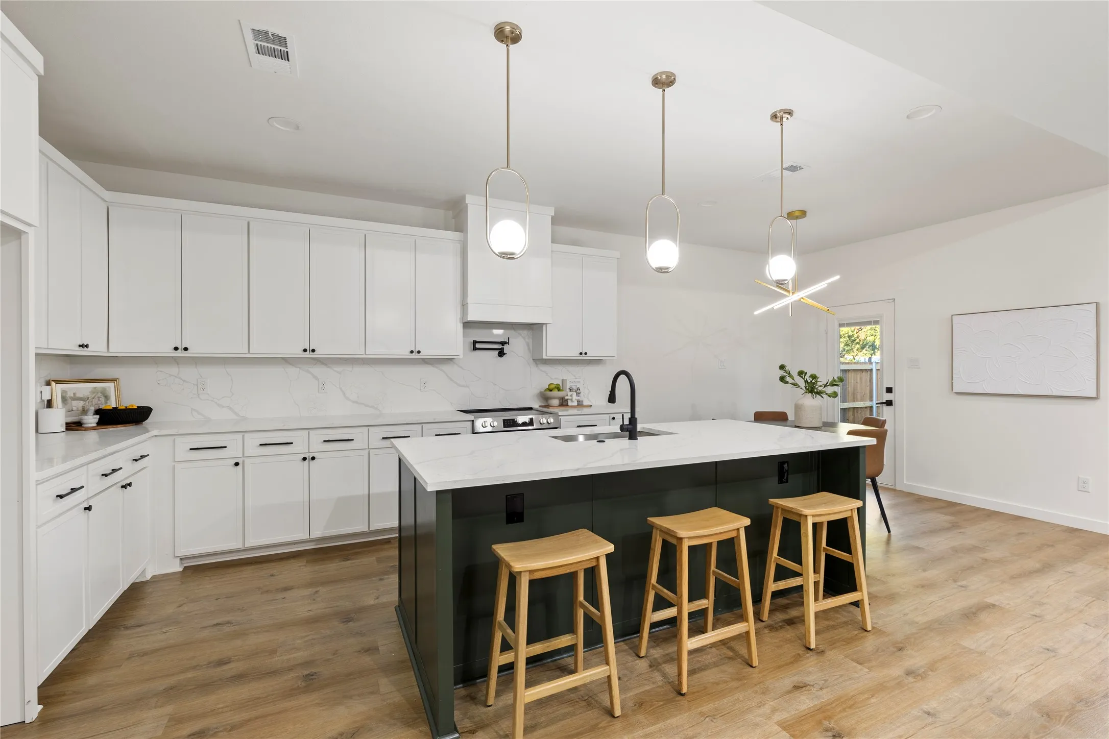 Kitchen featuring white cabinetry, a dark-toned island with a light-toned countertop, wood-finish flooring, and pendant lighting