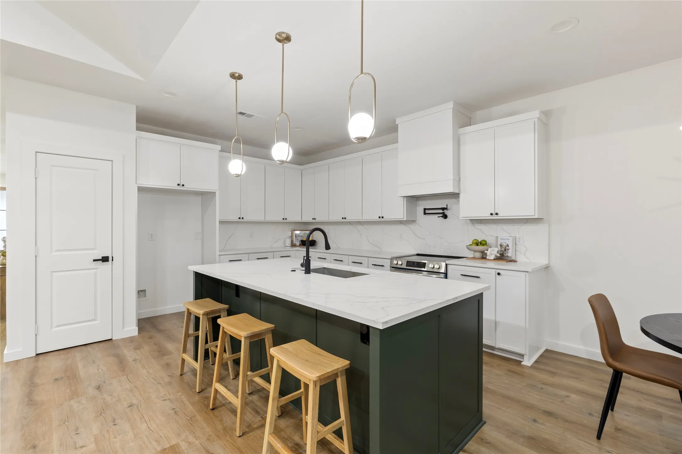 Kitchen featuring white cabinetry, a dark green island with a white countertop, wood-finish flooring, and pendant lighting