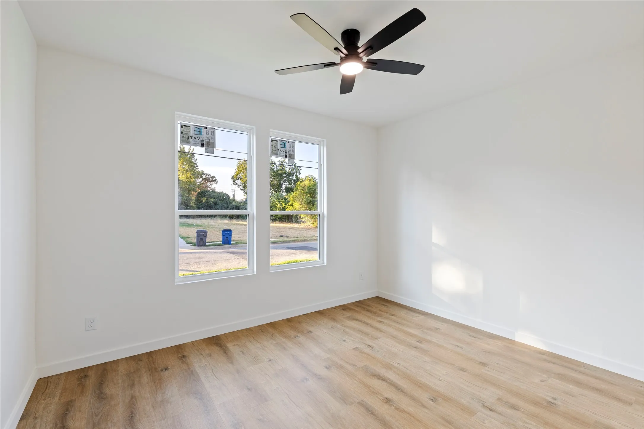 Wood-finish flooring, white walls, and a contemporary ceiling fan with integrated lighting