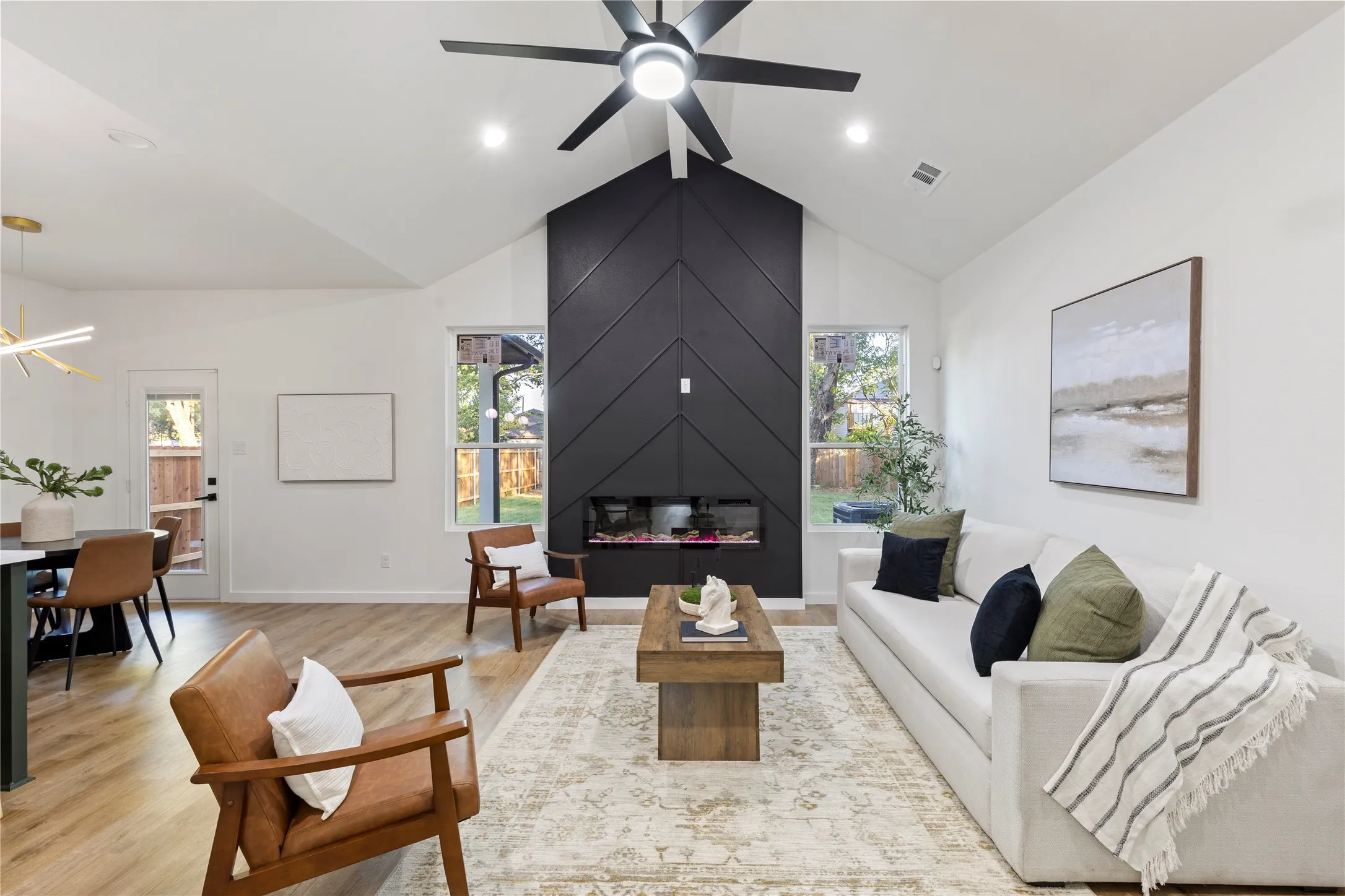 Vaulted ceiling, recessed lighting, wood-finish flooring, accent fireplace with an electric insert, and a ceiling fan with integrated lighting