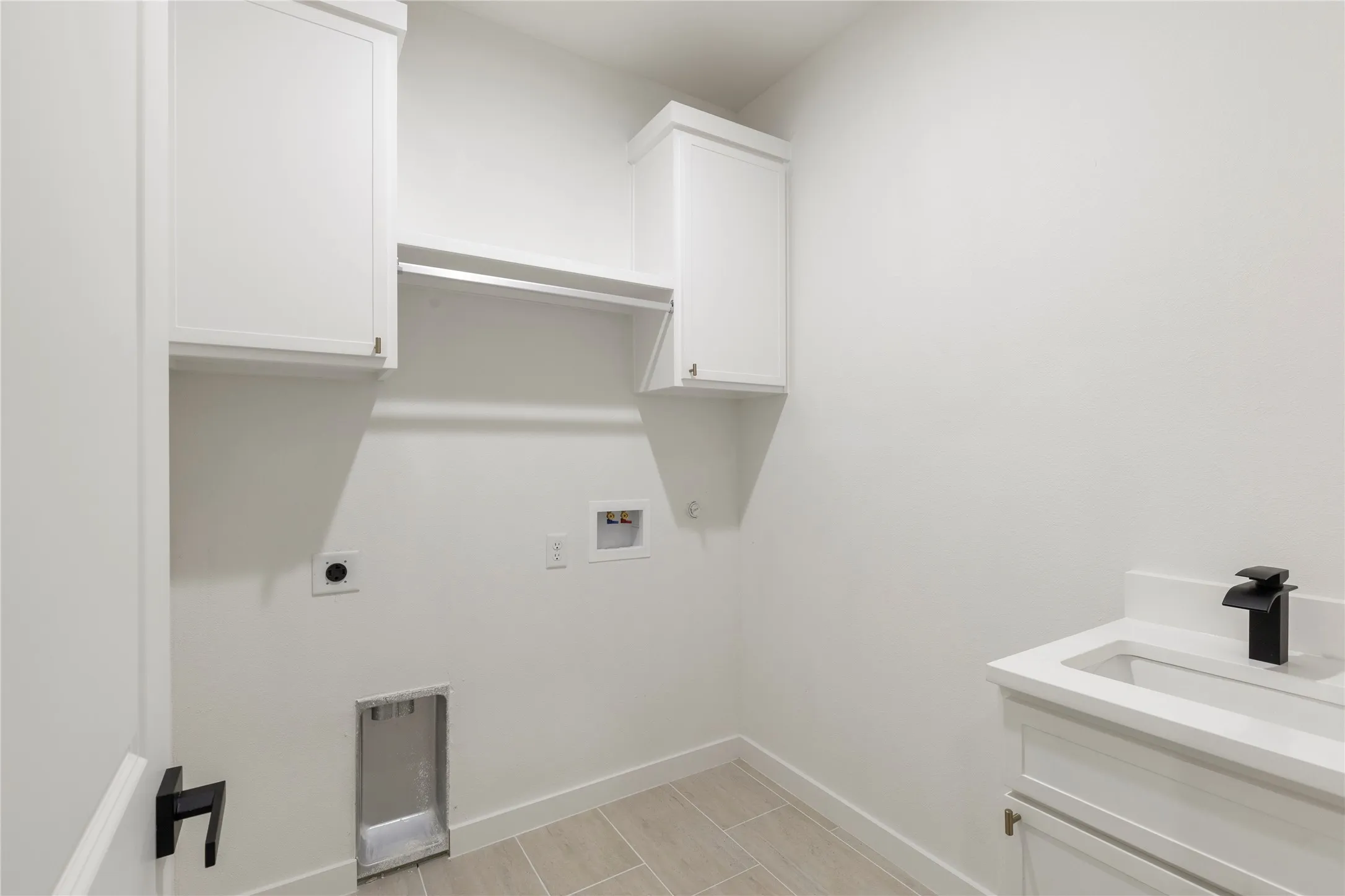 Laundry area featuring wood-finish tile flooring, white shaker-style cabinetry, and a single basin sink with a black modern faucet
