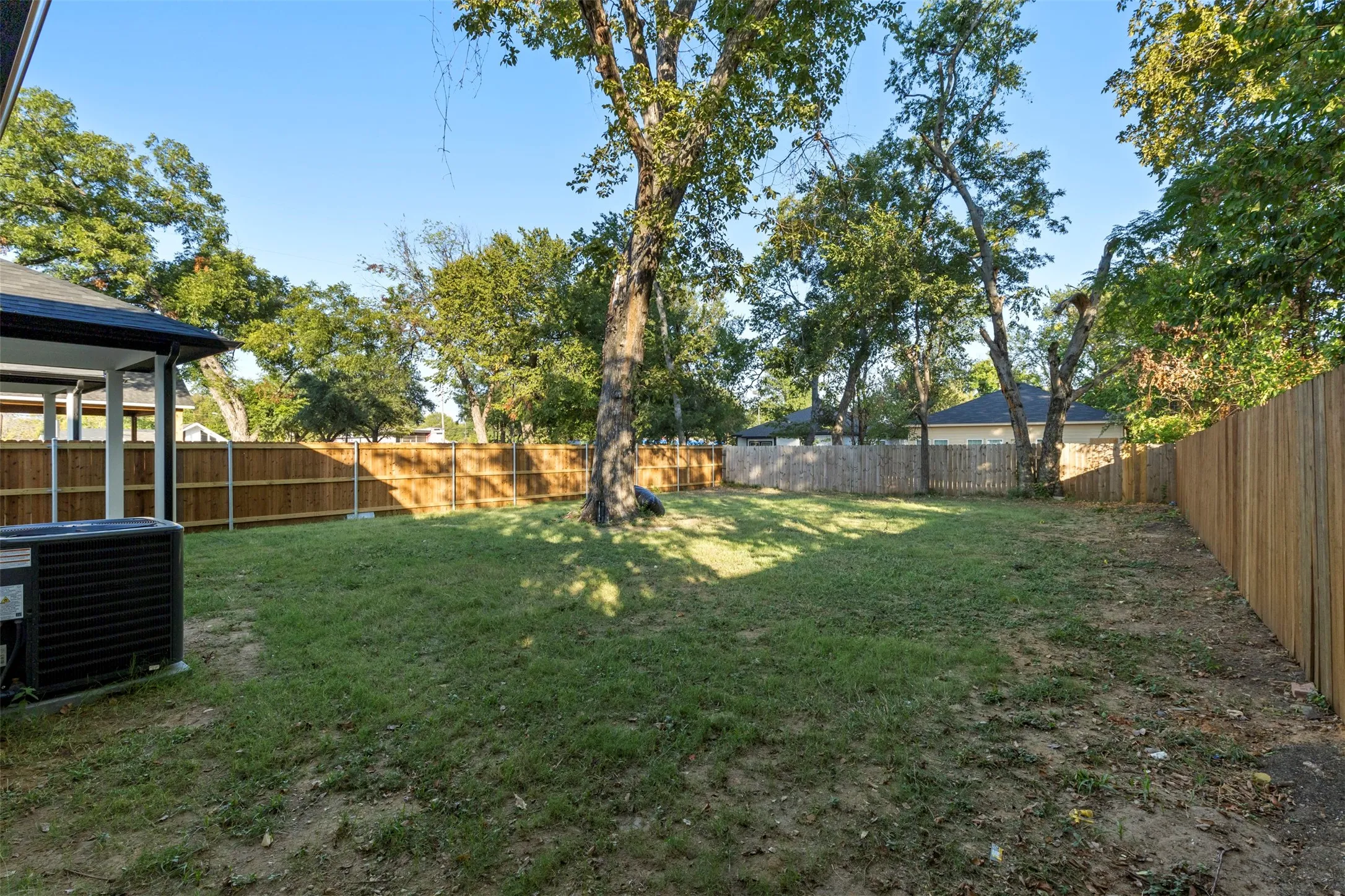 Expansive grassy yard with mature trees and wood fencing
