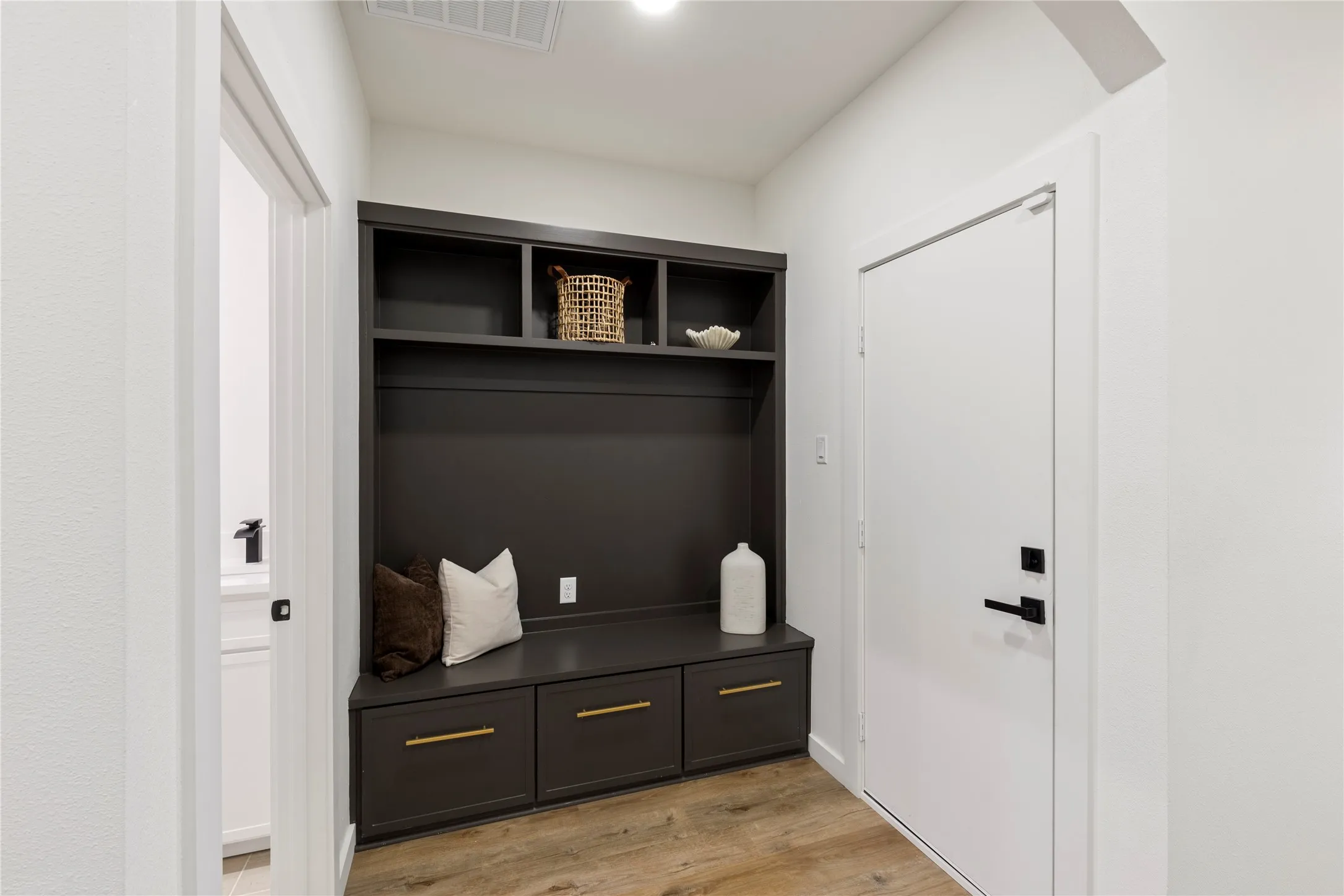Built-in cabinetry with bench seating, open shelving, and drawer storage with brass hardware