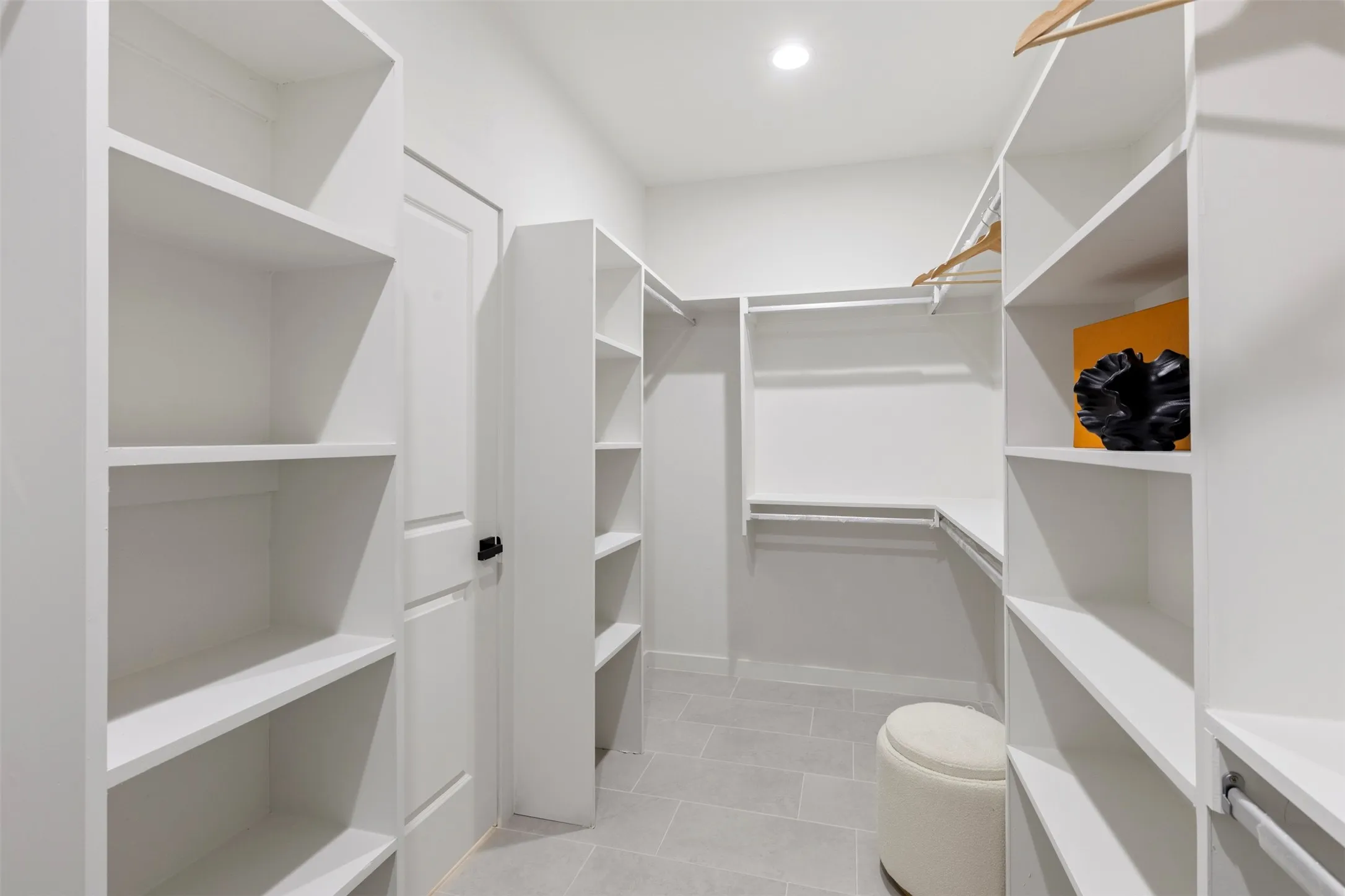 Walk-in closet featuring built-in shelving, hanging rods, and light gray tile flooring