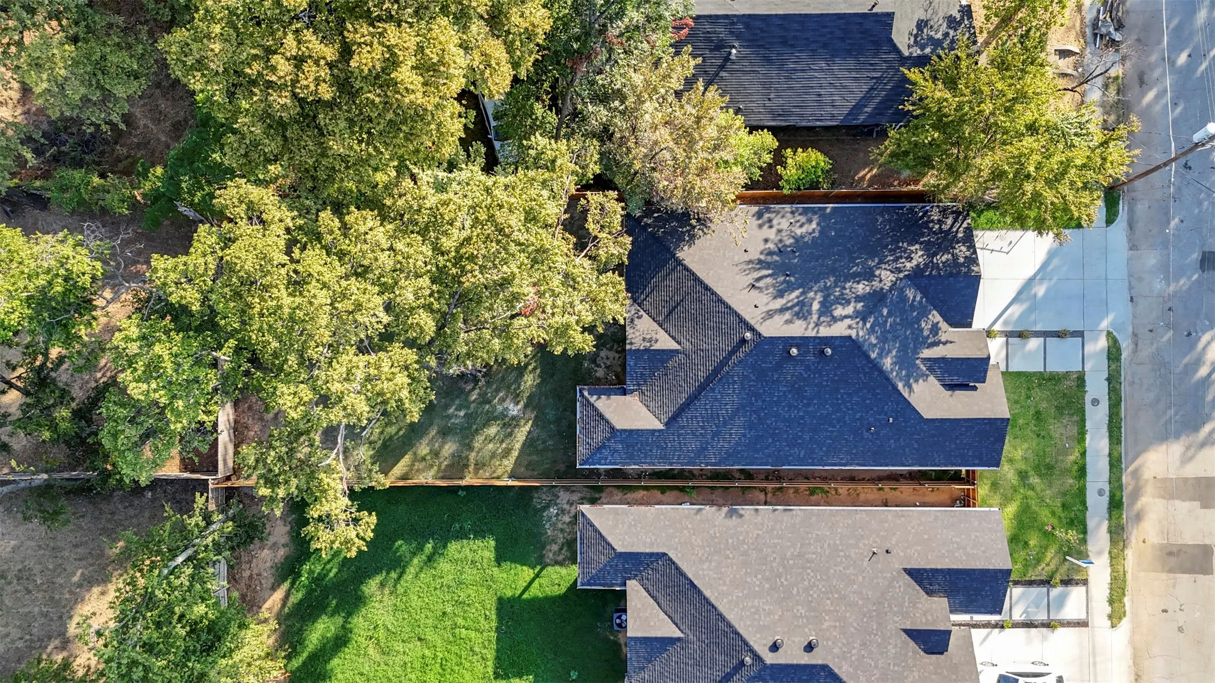 Black shingle roof with multiple gables, surrounded by mature trees