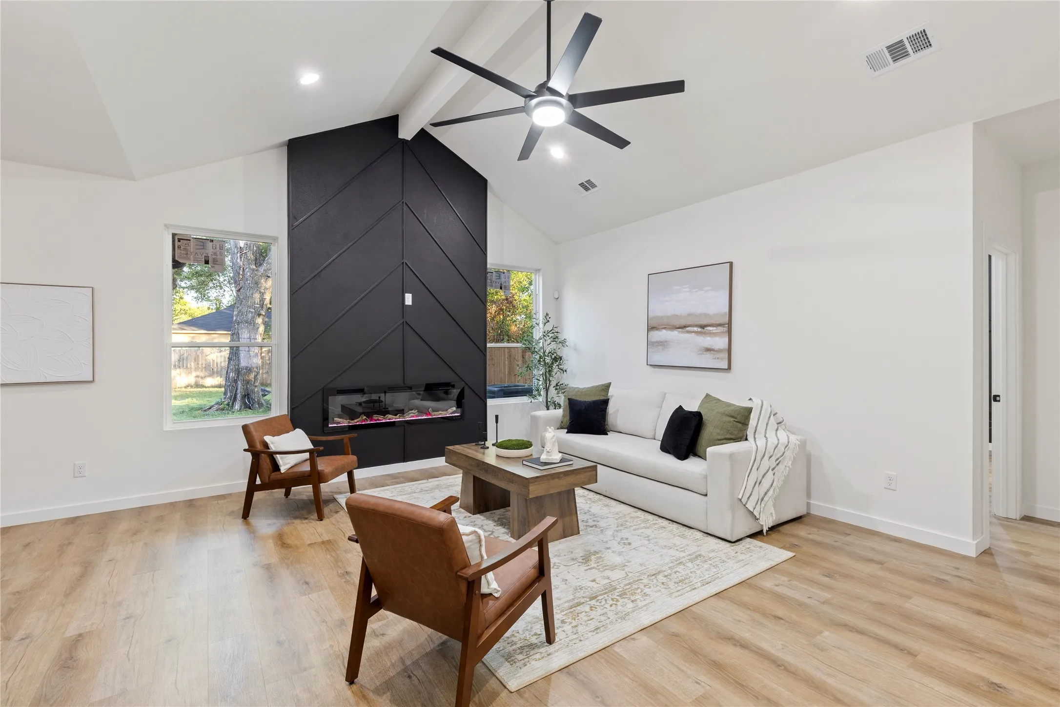 Vaulted ceilings with exposed beams, wood-finish flooring, and a contemporary linear fireplace