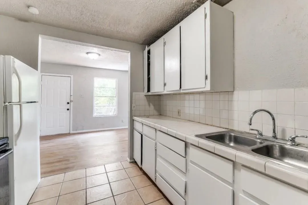 White cabinetry with stainless steel double basin sink and ceramic tile backsplash