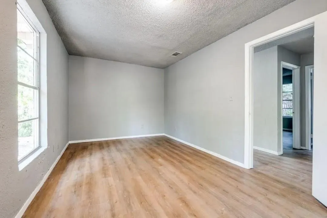 Wood-finish flooring, light gray wall finishes, a multi-pane window, and white trim throughout