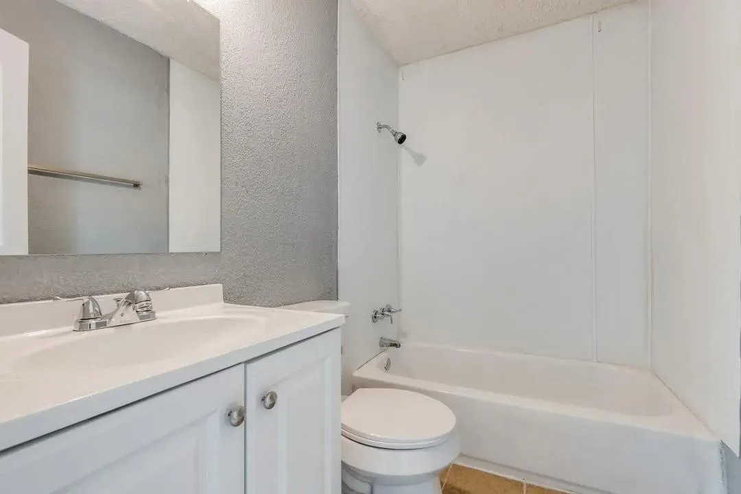 White vanity with integrated sink, chrome-finish faucet, and coordinating mirrored medicine cabinet