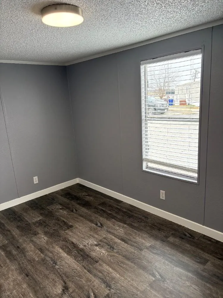 Wood-finish flooring, white trim, and a window with blinds