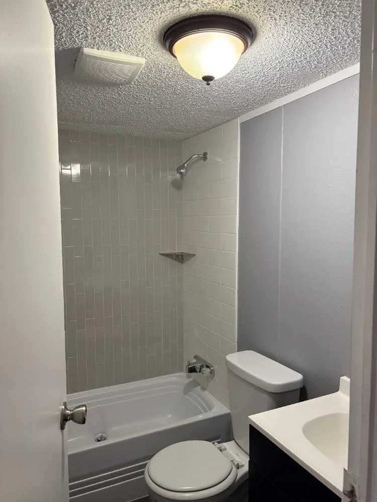 Bathtub with subway tile surround, integrated shower, and wall-mounted showerhead