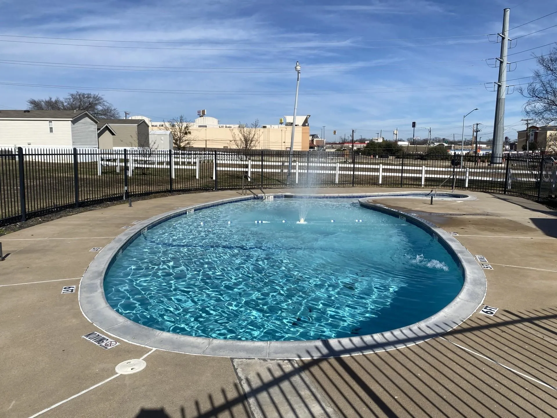 Freeform pool featuring a water fountain and surrounding concrete deck