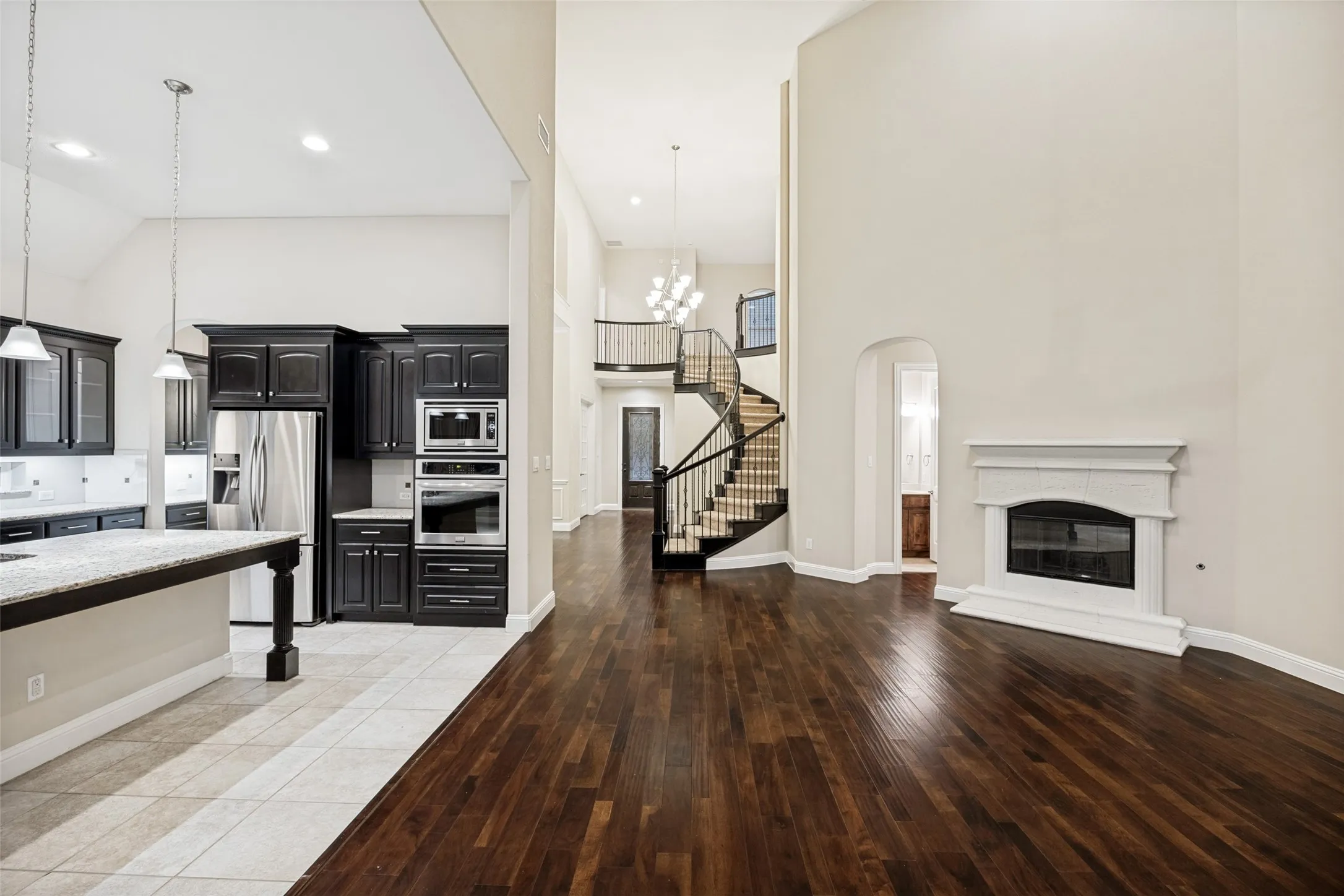 Wood-finish flooring, vaulted ceilings, and a built-in fireplace with a white mantel