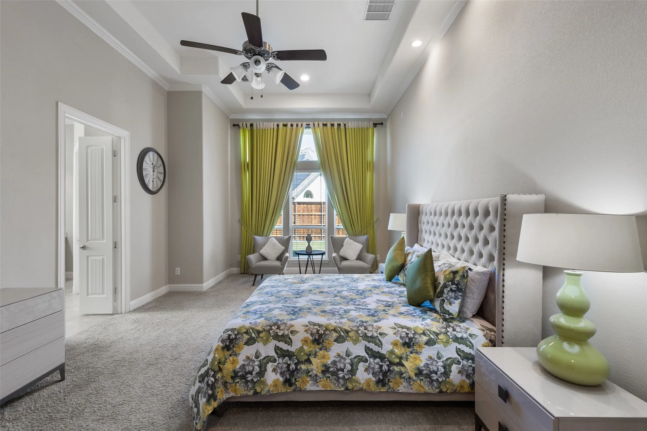 Carpeted room with a tray ceiling and a ceiling fan