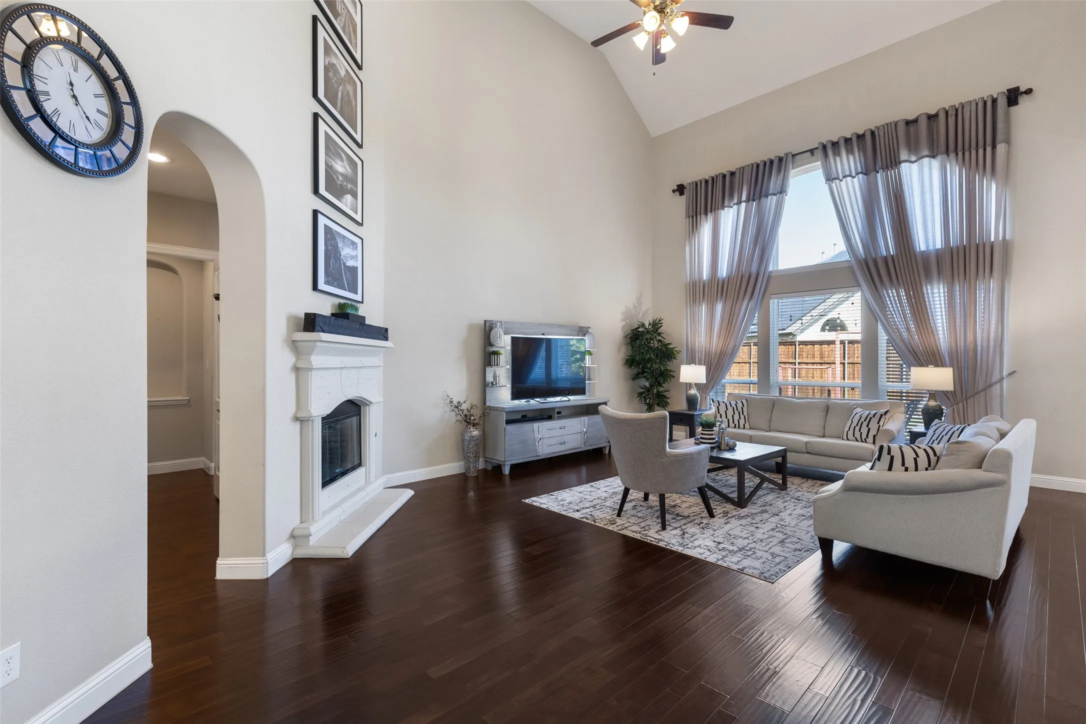 Vaulted ceiling, ceiling fan with integrated lighting, wood-finish flooring, floor-to-ceiling windows, and a built-in fireplace