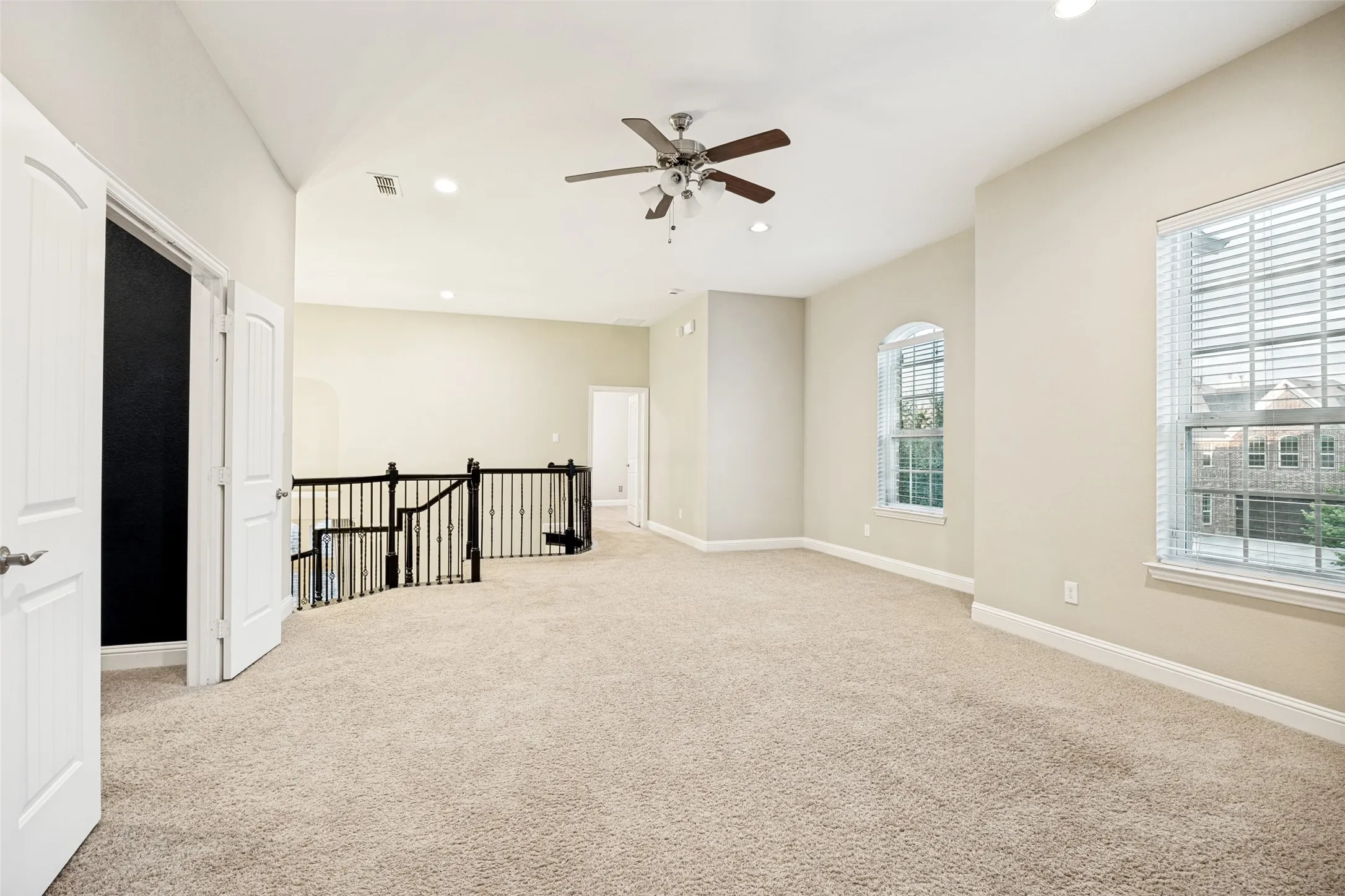 Carpeted open-concept space featuring a ceiling fan, recessed lighting, and multiple windows with blinds