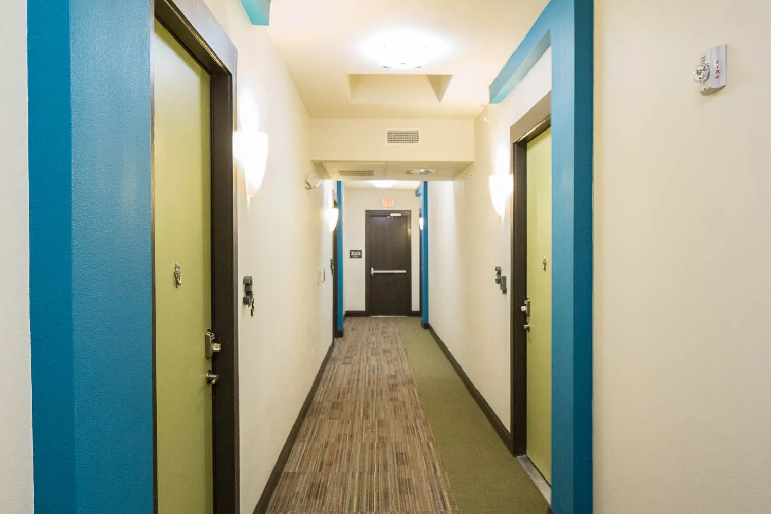 Corridor with recessed lighting, wall sconces, and a combination of carpet and wood-finish flooring