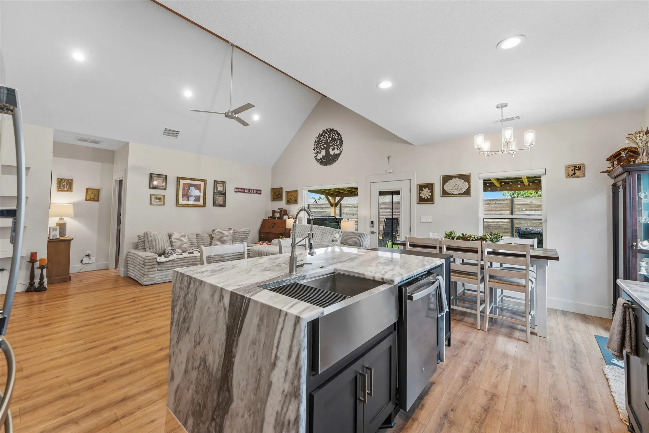 Kitchen island featuring a waterfall countertop with an undermount farmhouse sink and integrated dishwasher