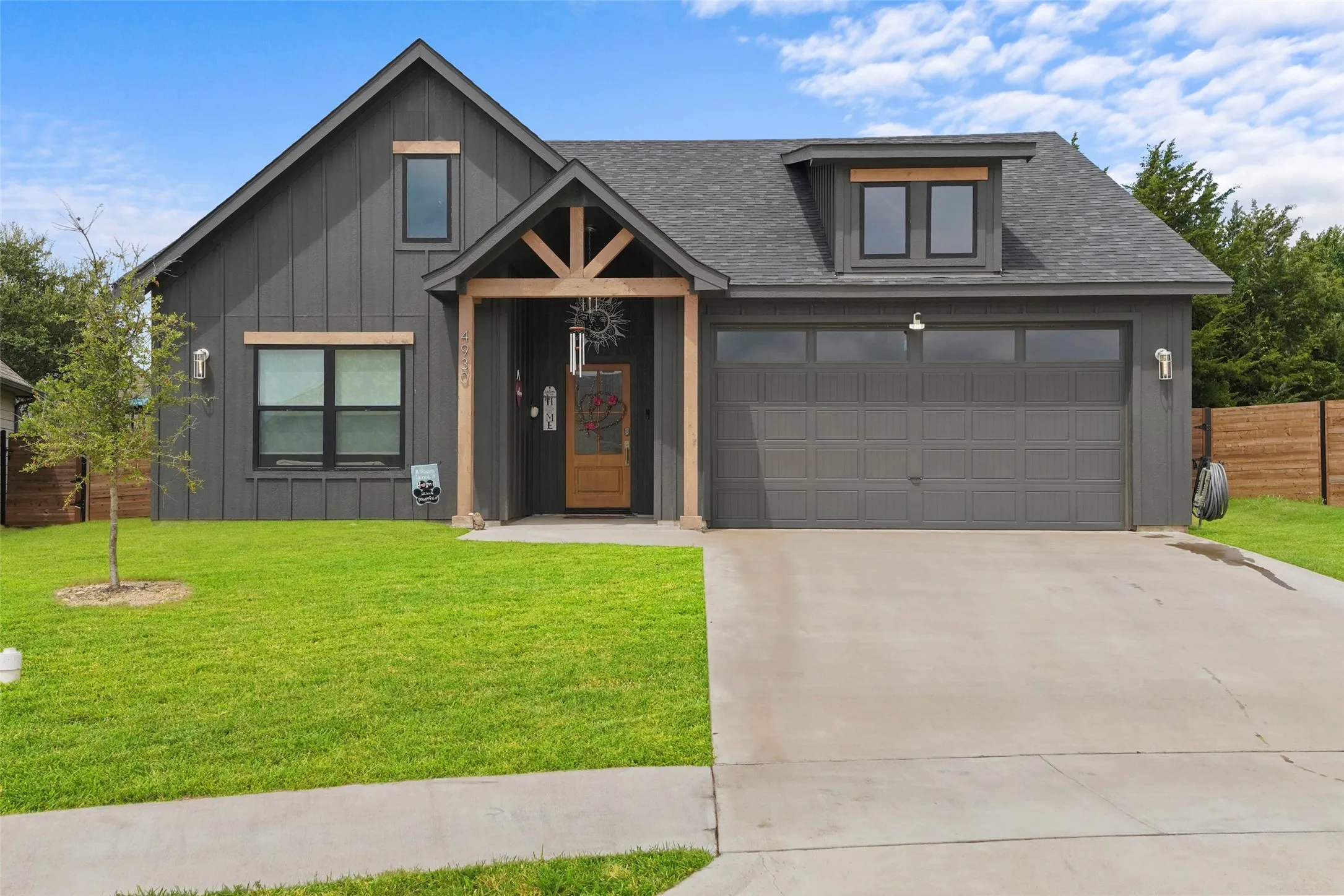 Contemporary farmhouse-style exterior featuring dark vertical siding and natural wood accents