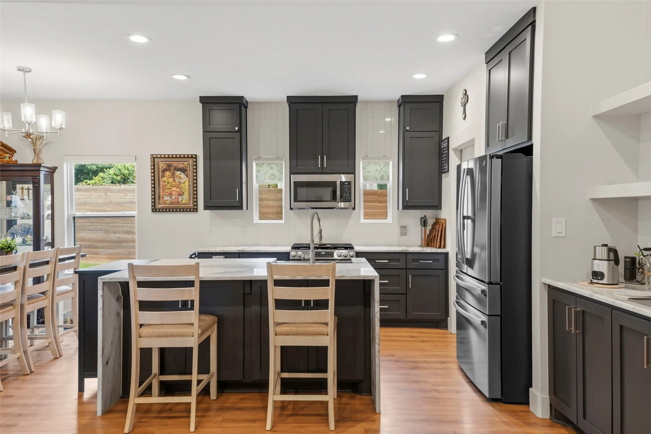 Spacious kitchen featuring an island with stone countertops, dark wood-finish cabinetry, stainless steel appliances, and recessed lighting