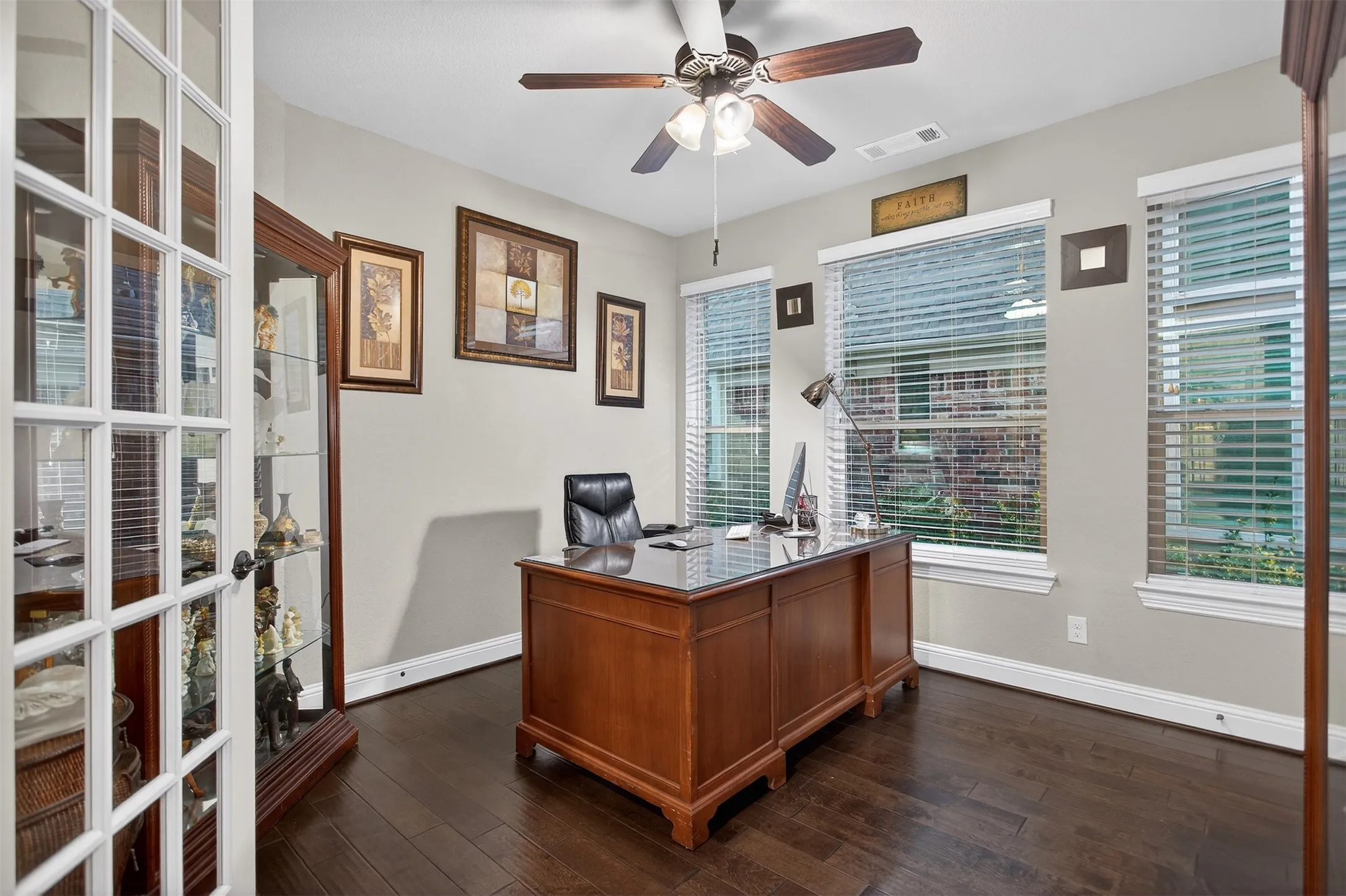 Wood-finish flooring, multiple windows, ceiling fan, and French doors