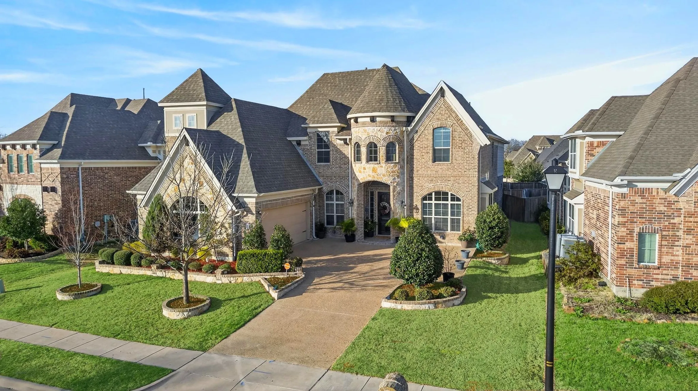 Brick and stone exterior with a turret, arched entry, and pitched rooflines