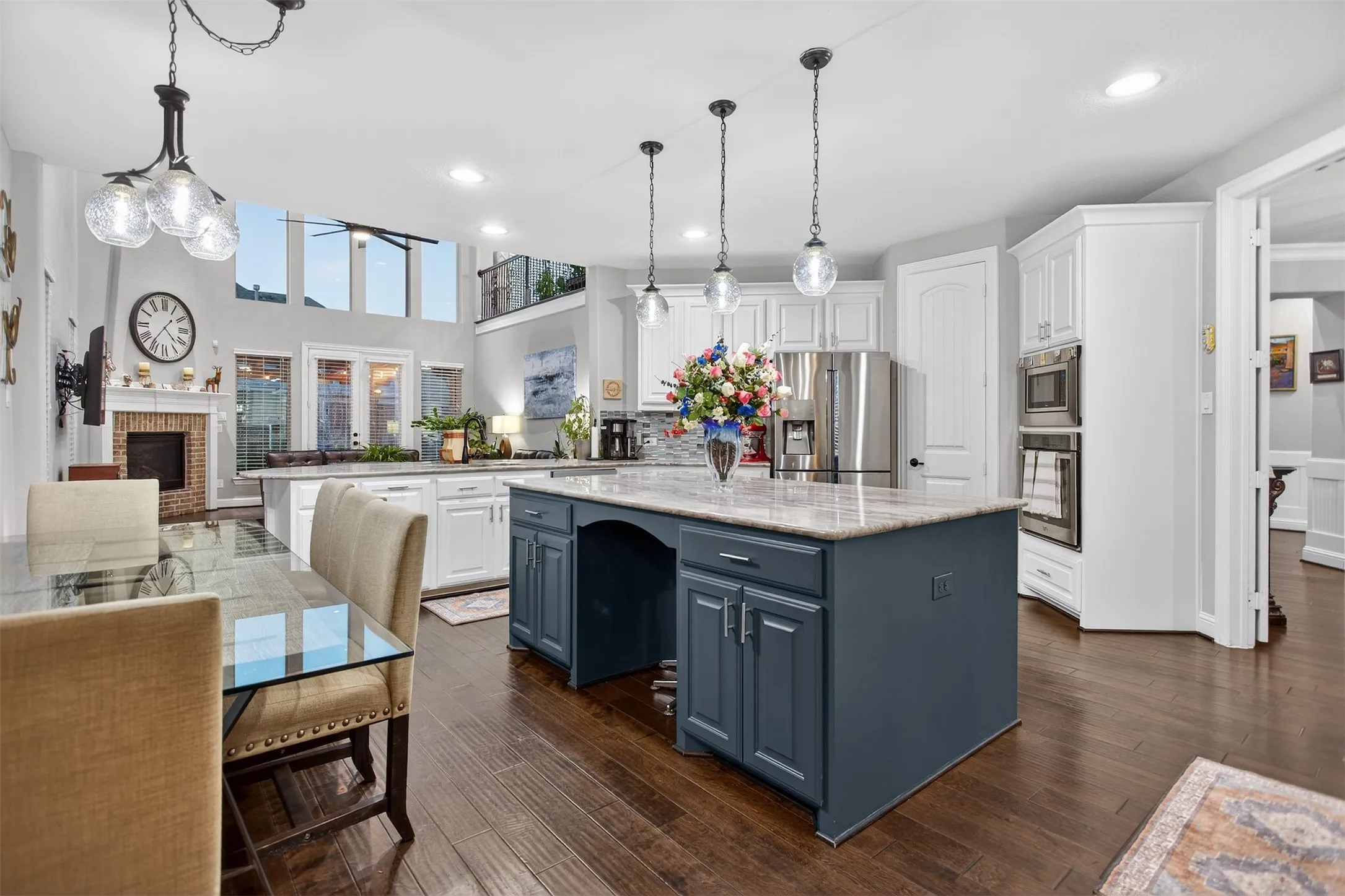 Open-concept kitchen with a two-story ceiling, a large kitchen island, stainless steel appliances, and wood-finish flooring