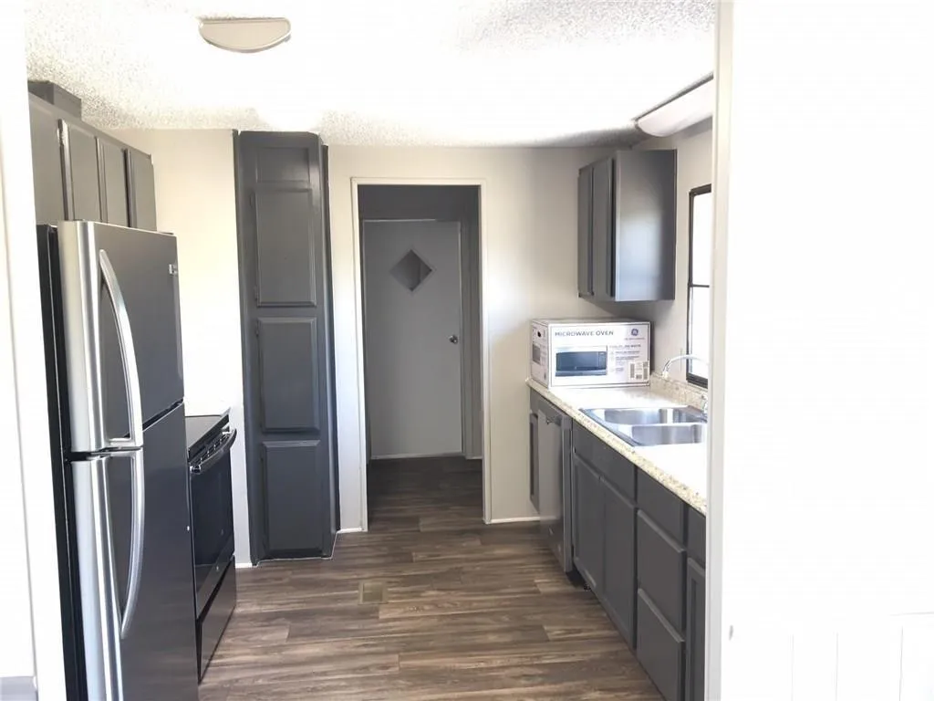 Kitchen featuring wood-finish flooring, dark cabinetry, and light countertops