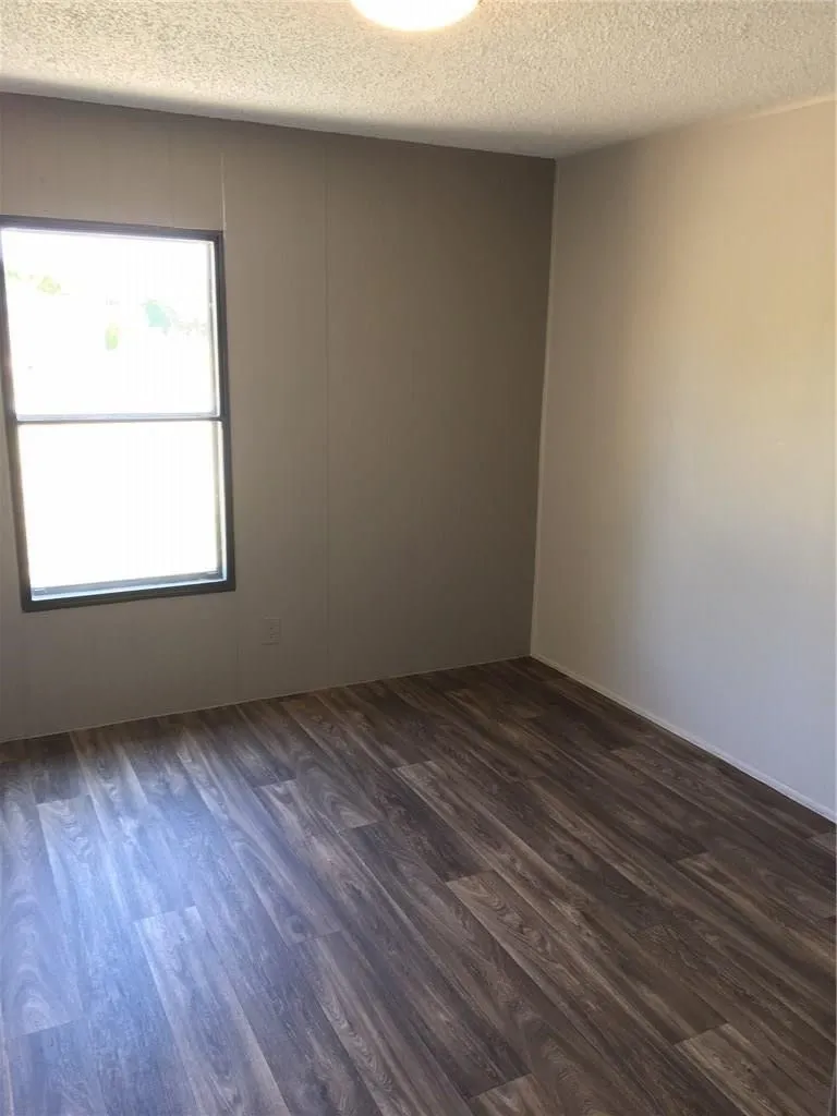Wood-finish flooring with a dark tone, neutral wall finishes, and a single window with dark trim